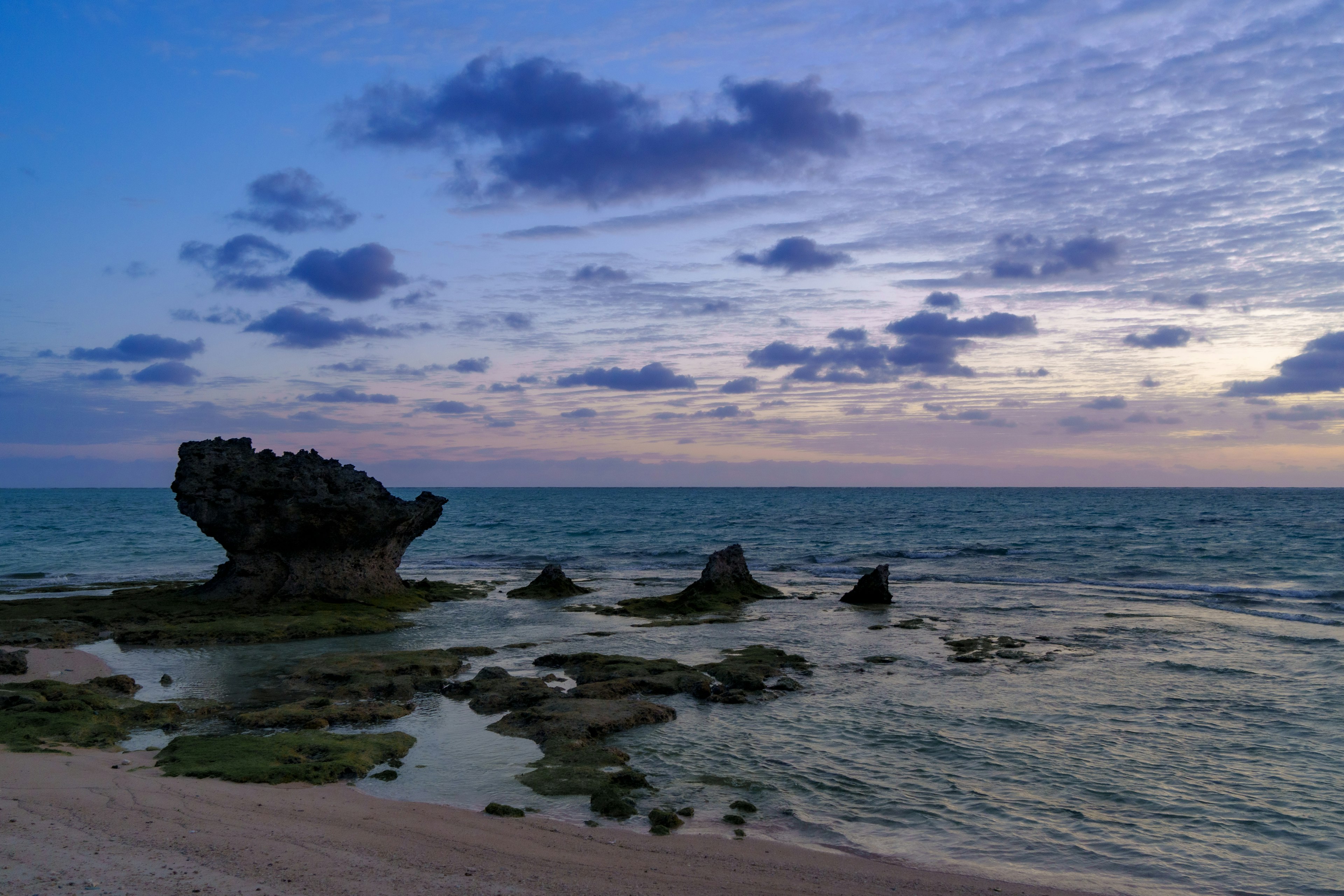 Scena costiera al crepuscolo con una formazione rocciosa e mare calmo