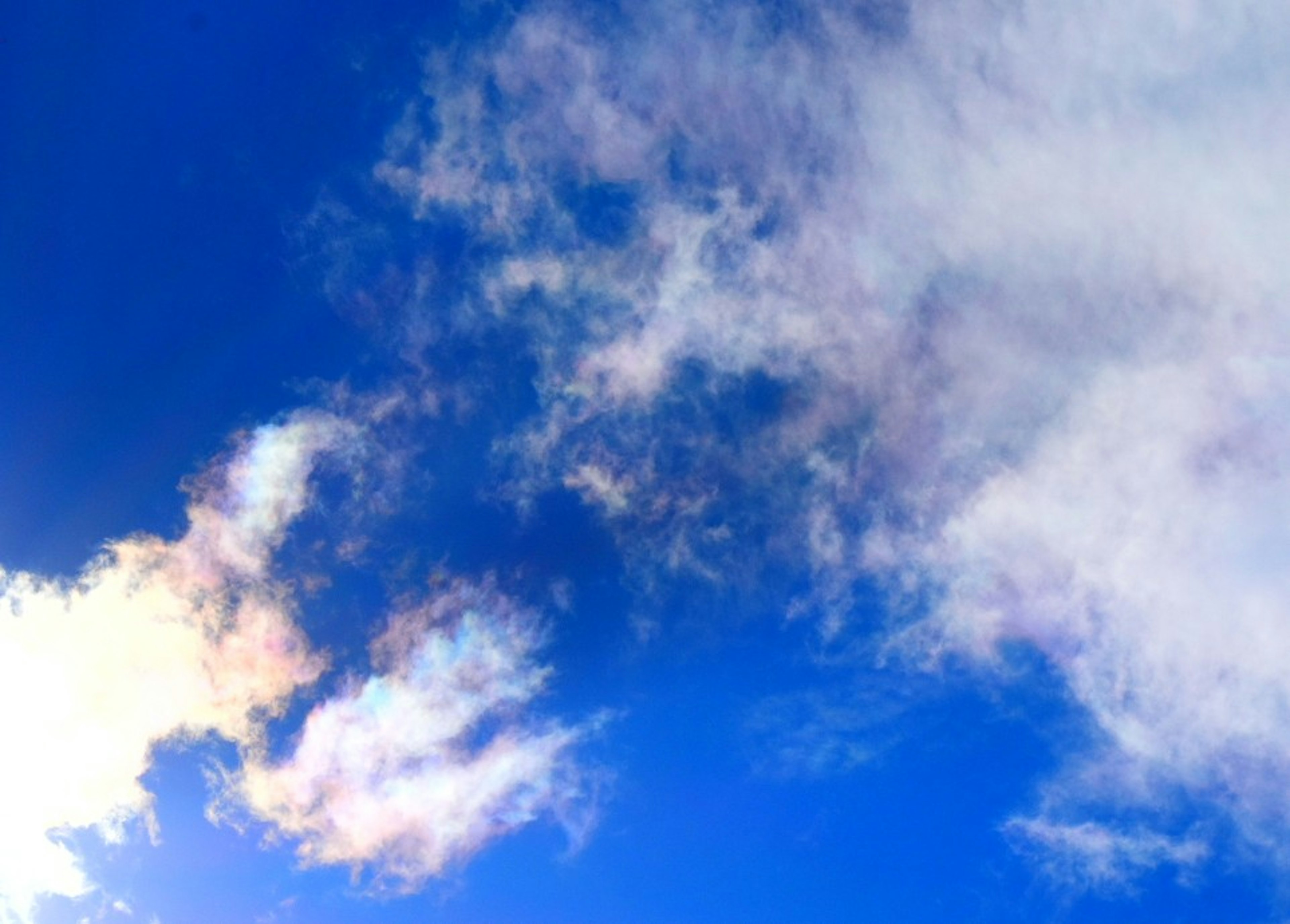 Nubes finas reflejando luz iridiscente contra un cielo azul