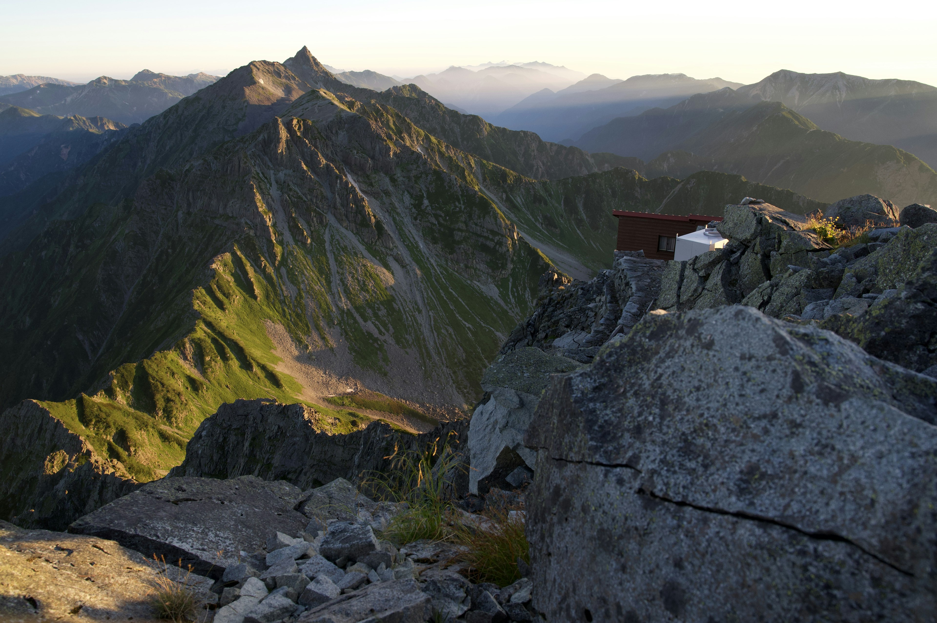 Vista mozzafiato da un picco montano con montagne verdi e terreno roccioso