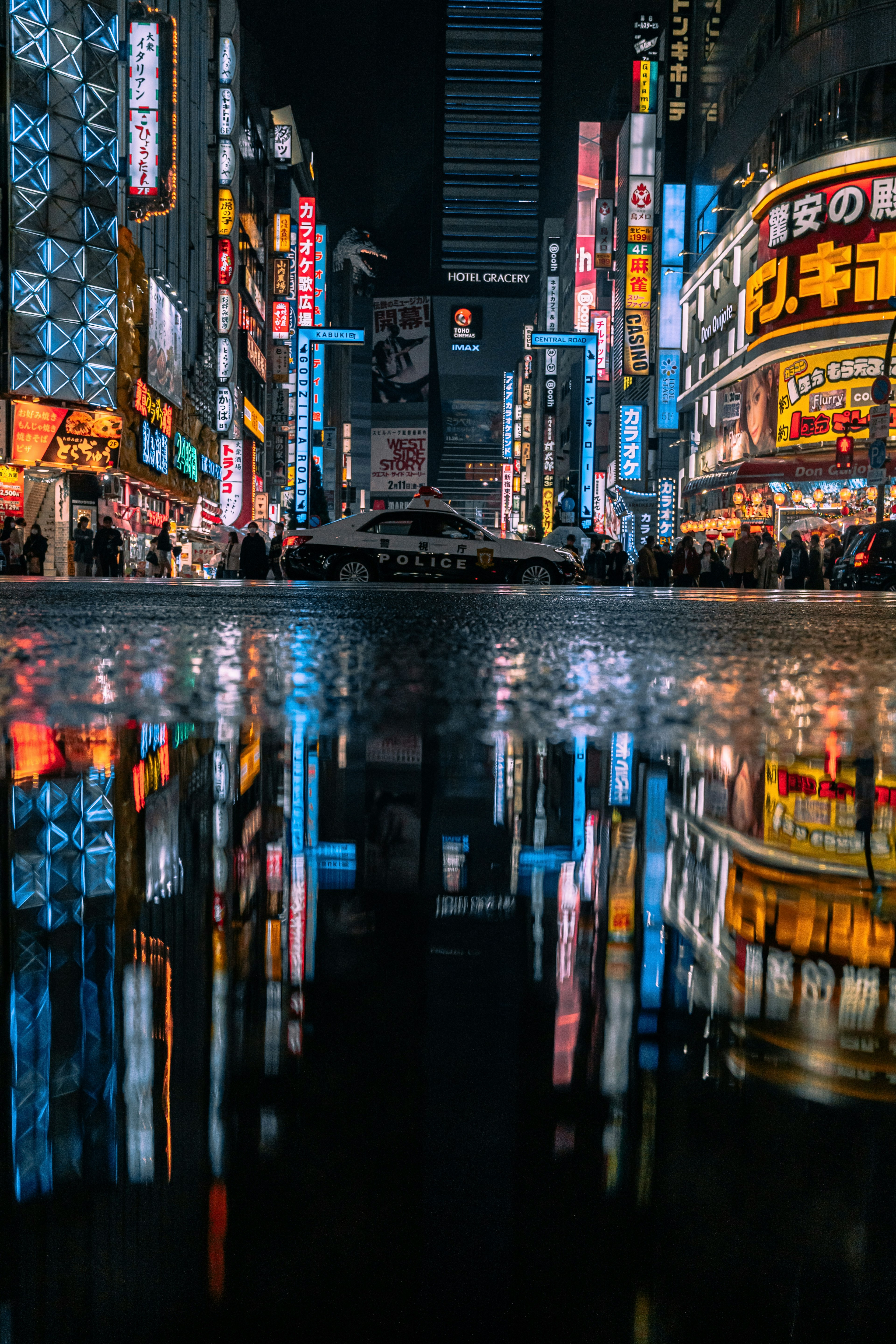 夜の街並みを映す水たまりに映るネオンの光