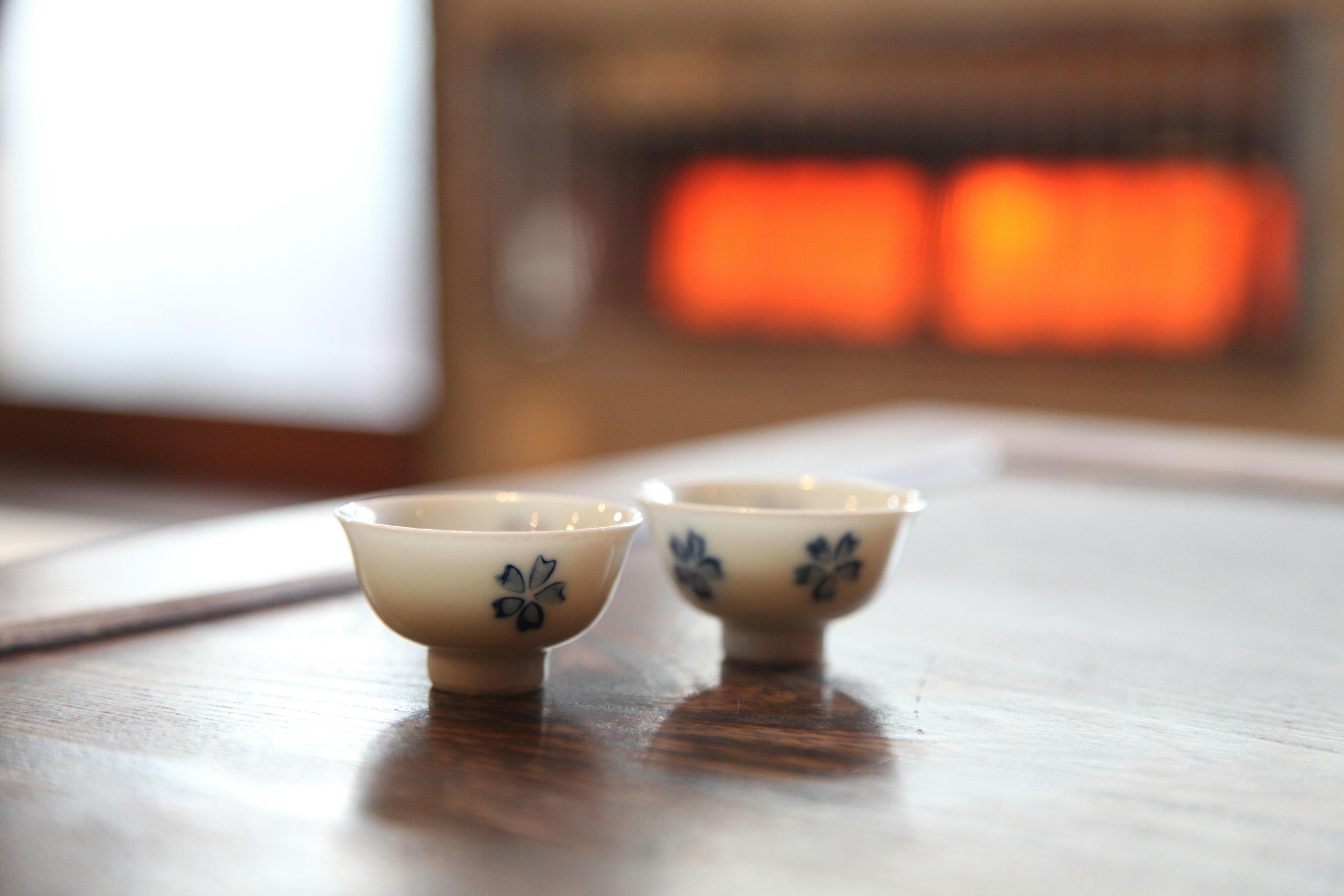 Two beautiful ceramic bowls placed on a wooden table with warm orange heating in the background