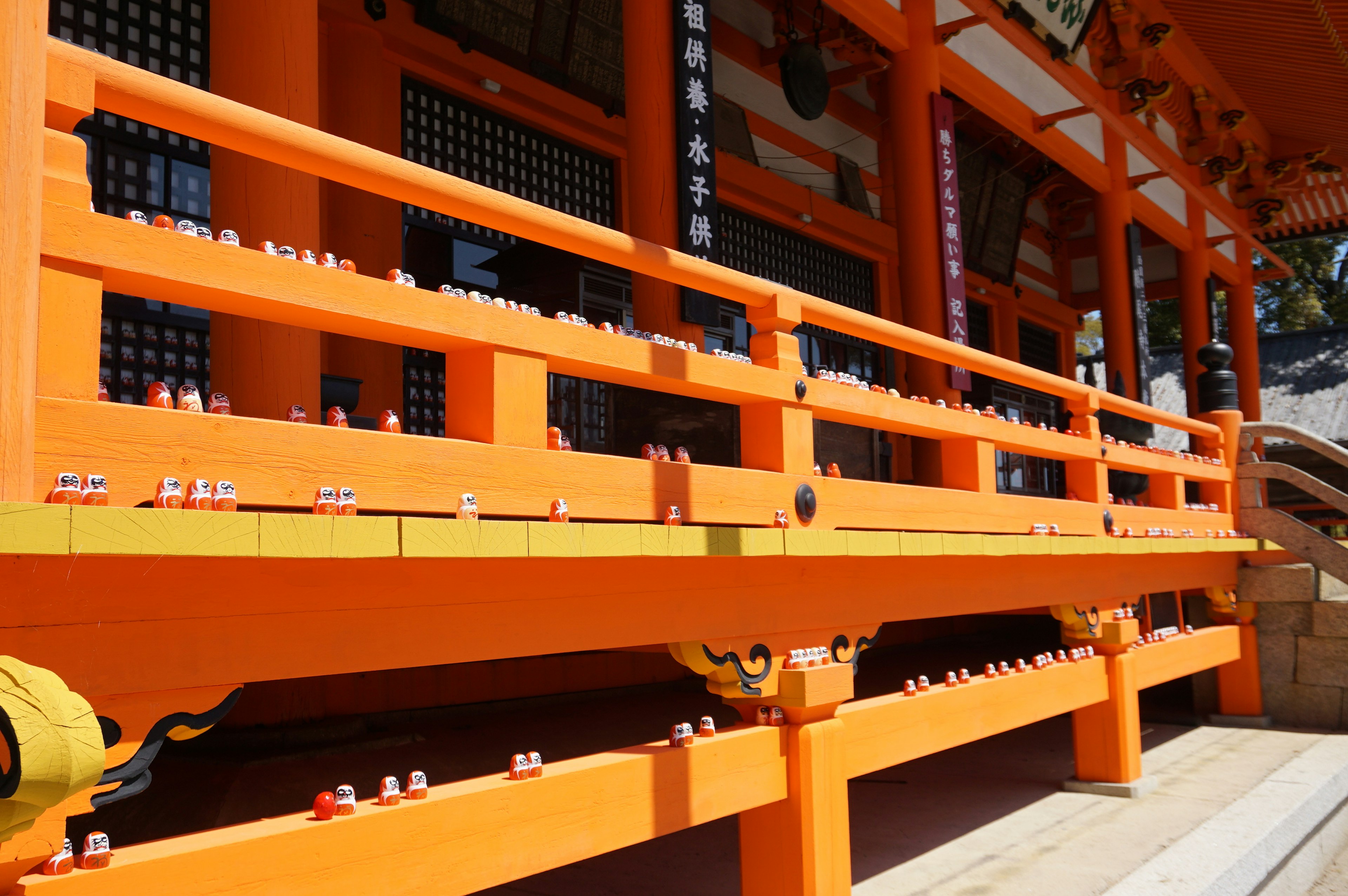 Vibrant orange railing of a shrine featuring small offerings