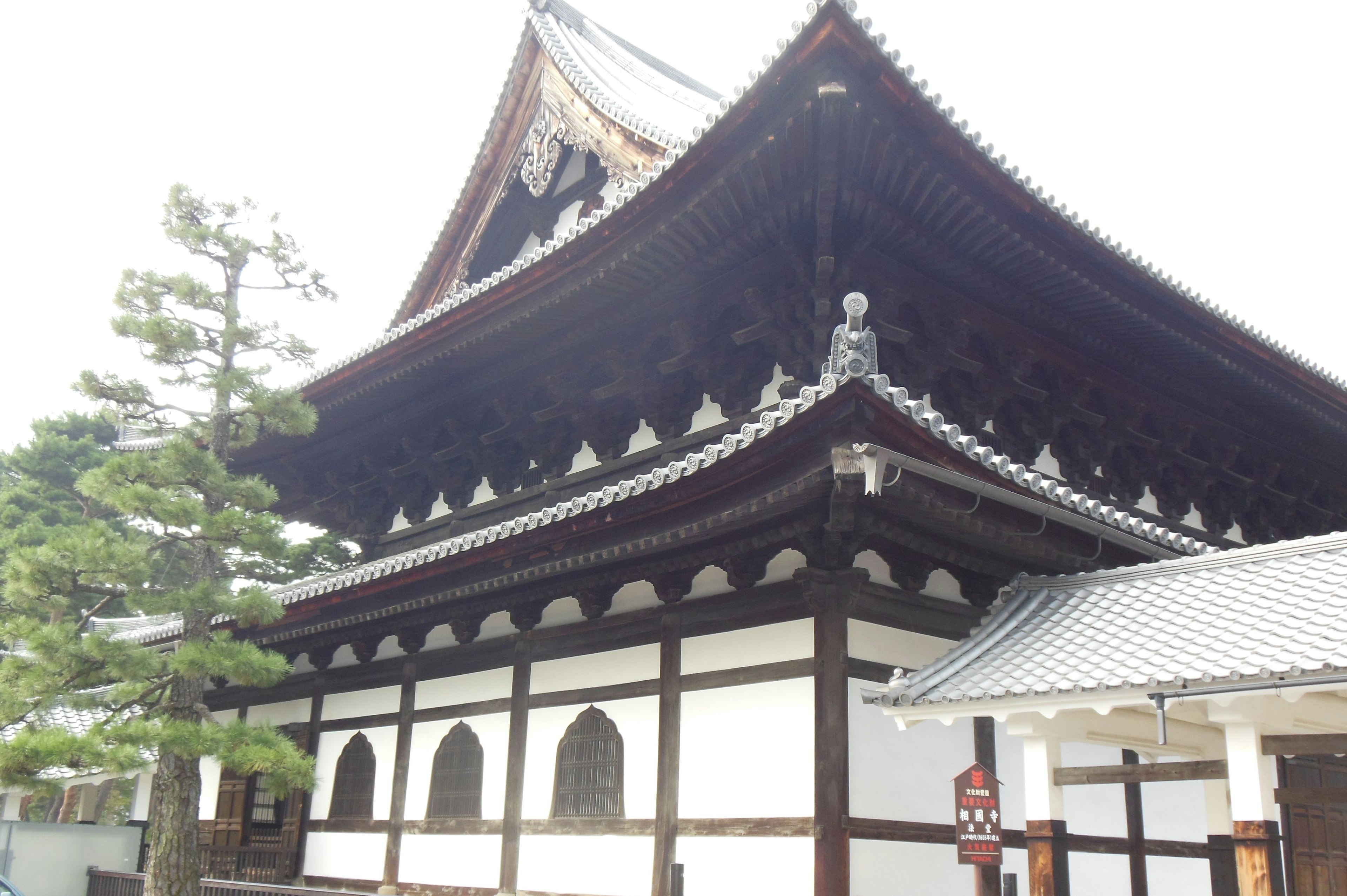 Large temple building with traditional Japanese architecture intricate roof design surrounding trees