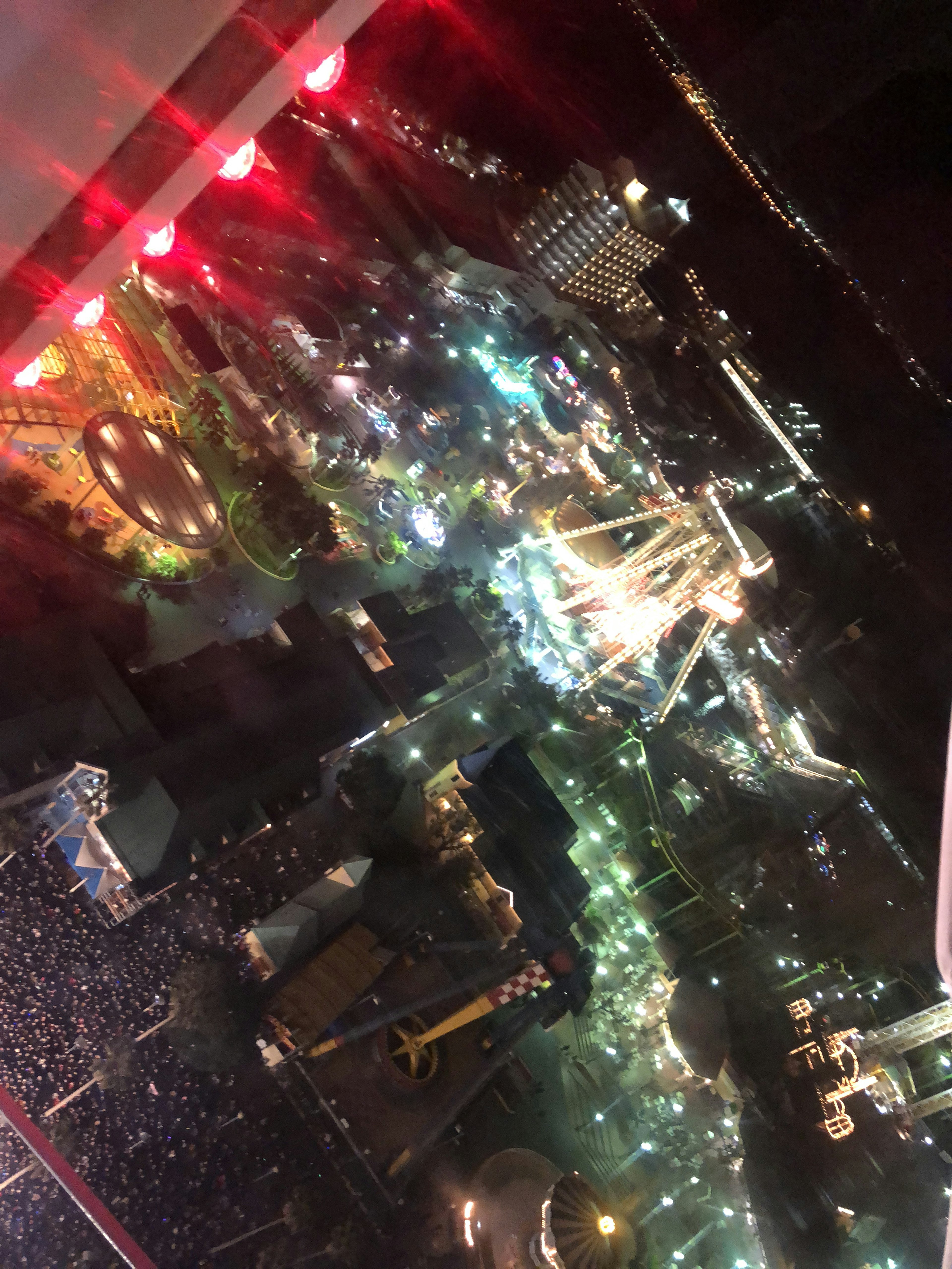 Vista aérea de un parque de atracciones iluminado por la noche con atracciones coloridas y luces vibrantes