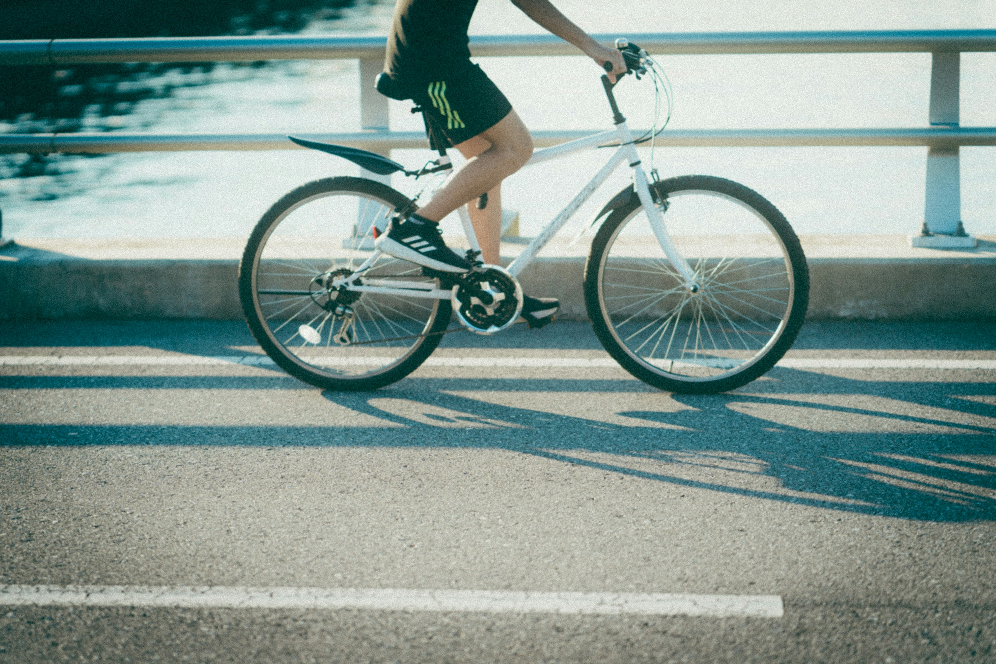 Eine Person auf einem Fahrrad mit sichtbaren Rädern und Beinen auf einer Straße