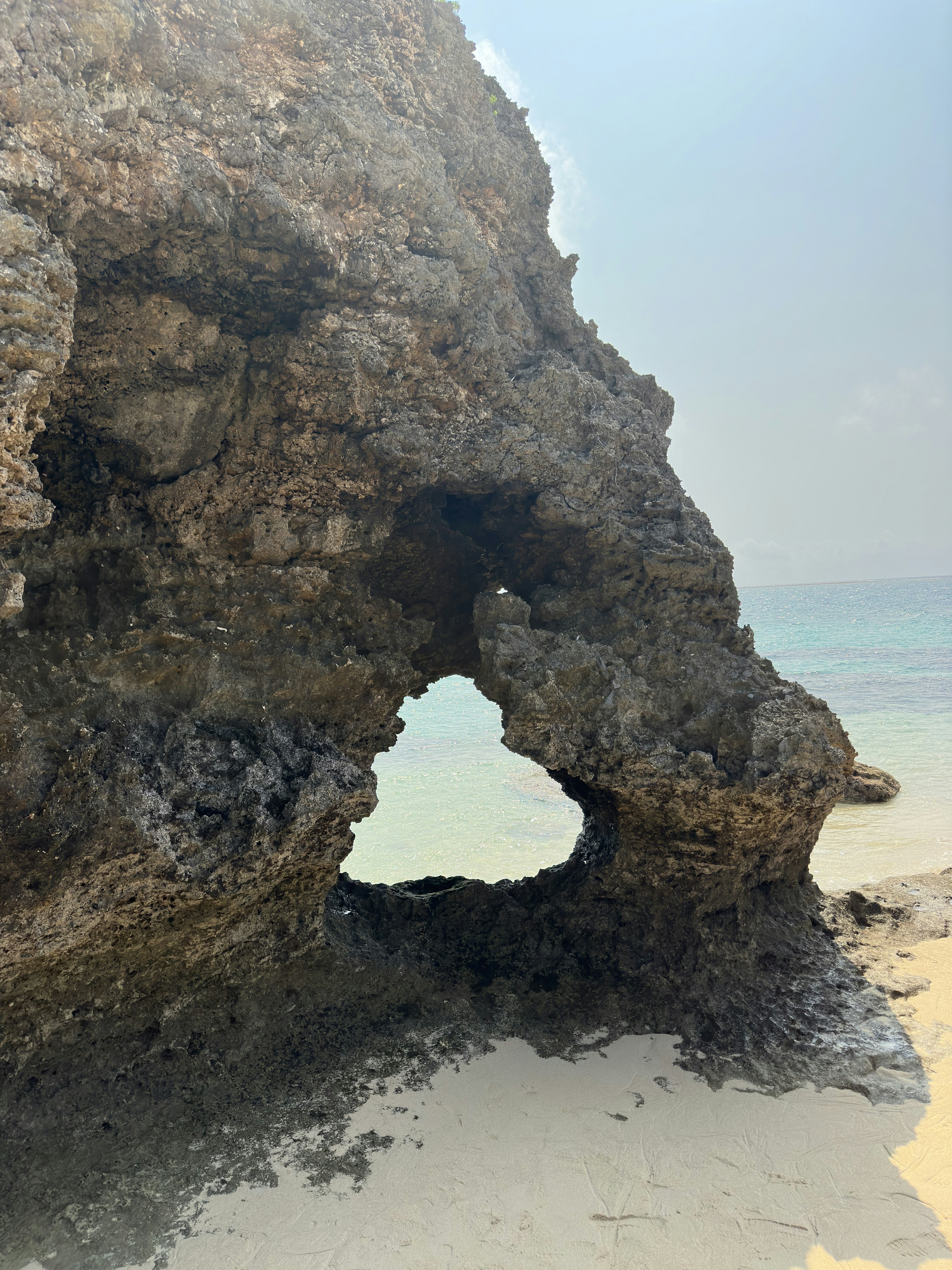 Forma rocciosa unica con un arco su una spiaggia sabbiosa