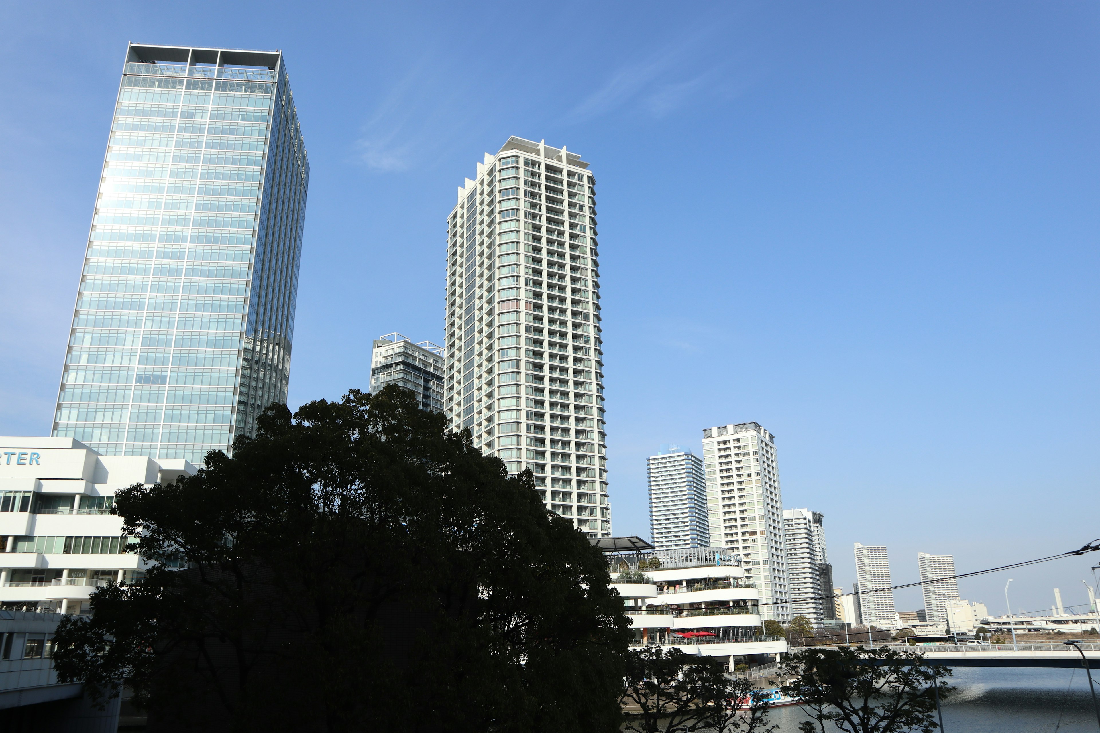 Cityscape featuring skyscrapers with clear blue sky and reflections on water