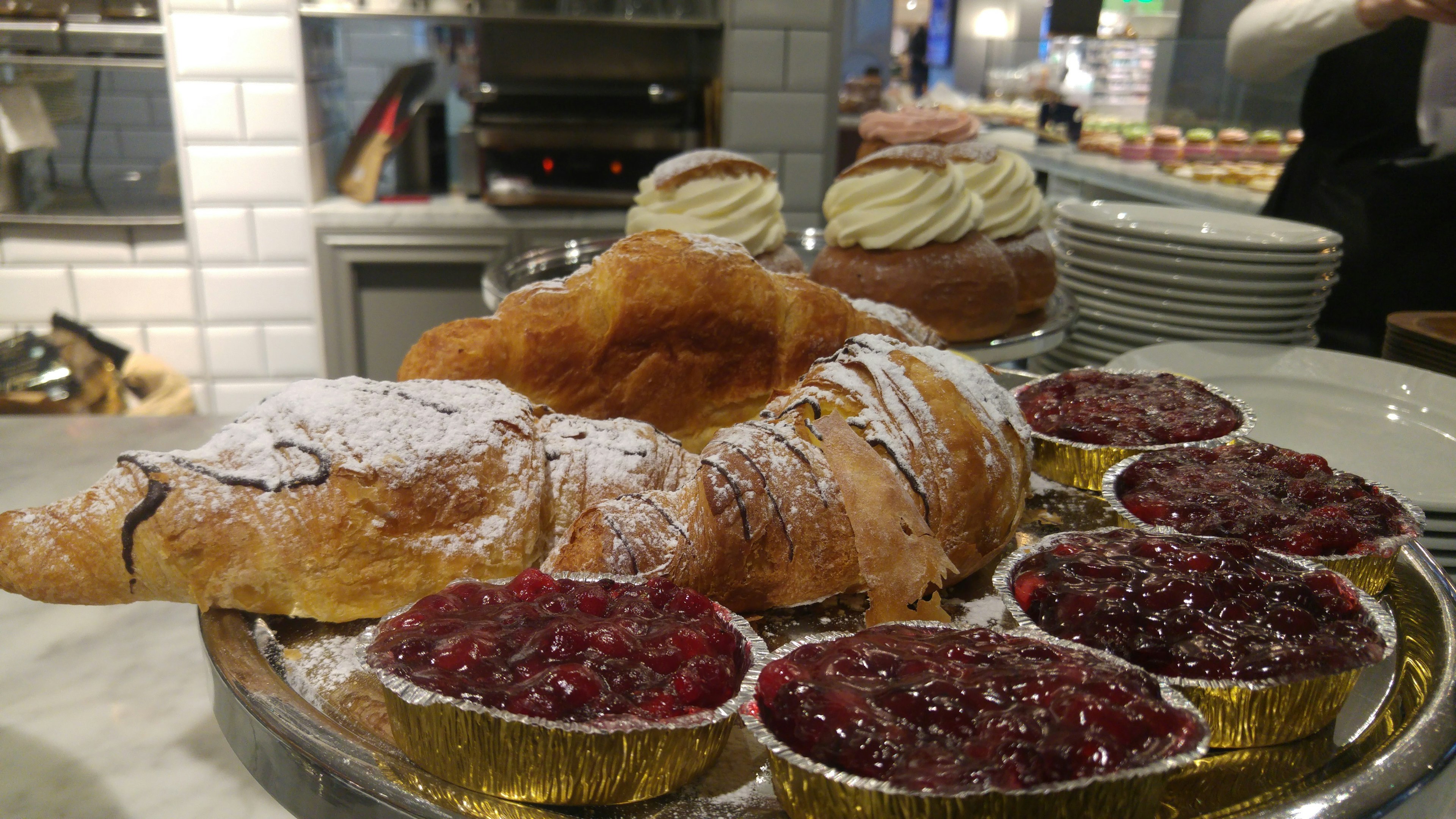 Croissant mit Puderzucker bestäubt und Beeren-Saucen-Törtchen