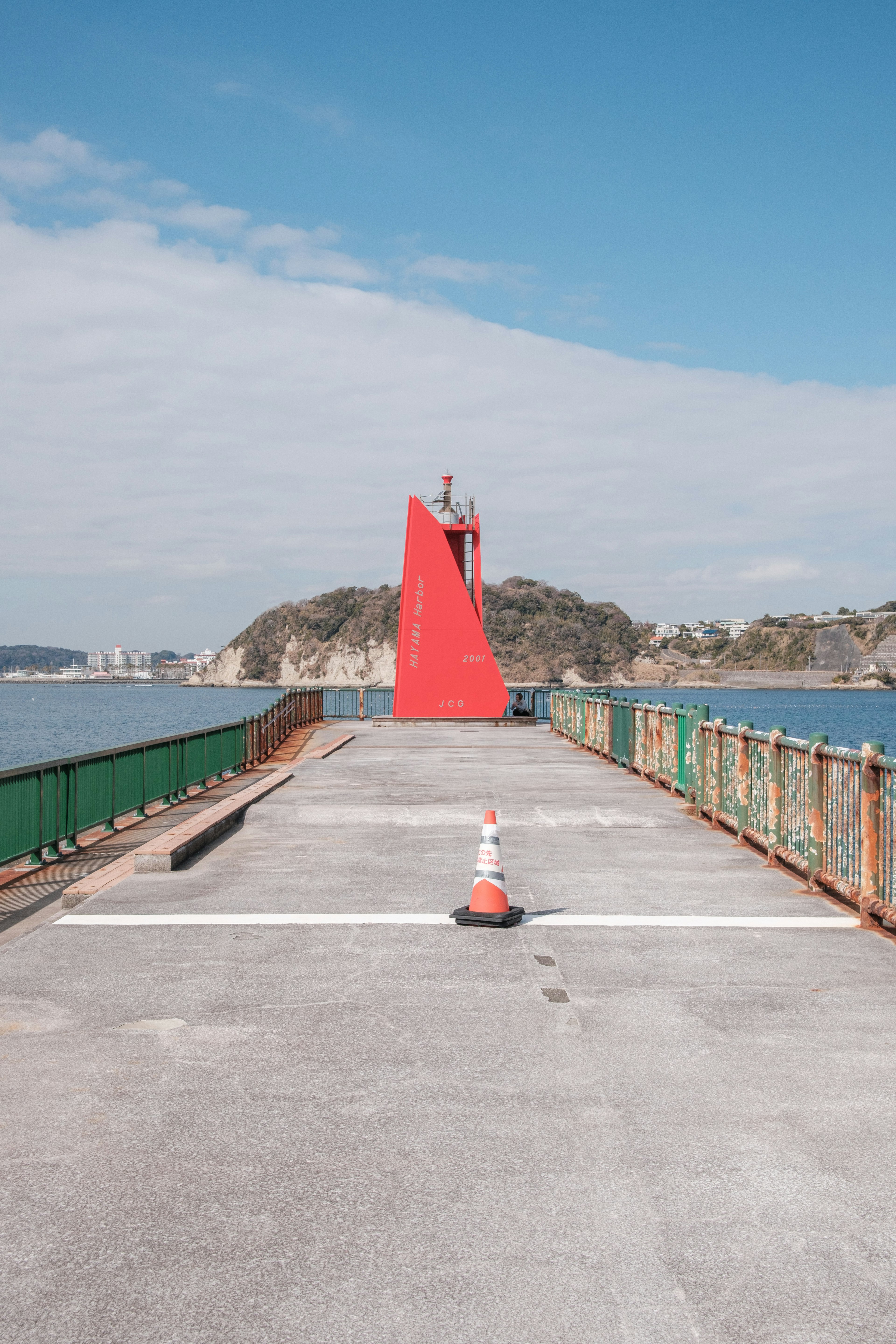 View of a pier with a red lighthouse and blue sky