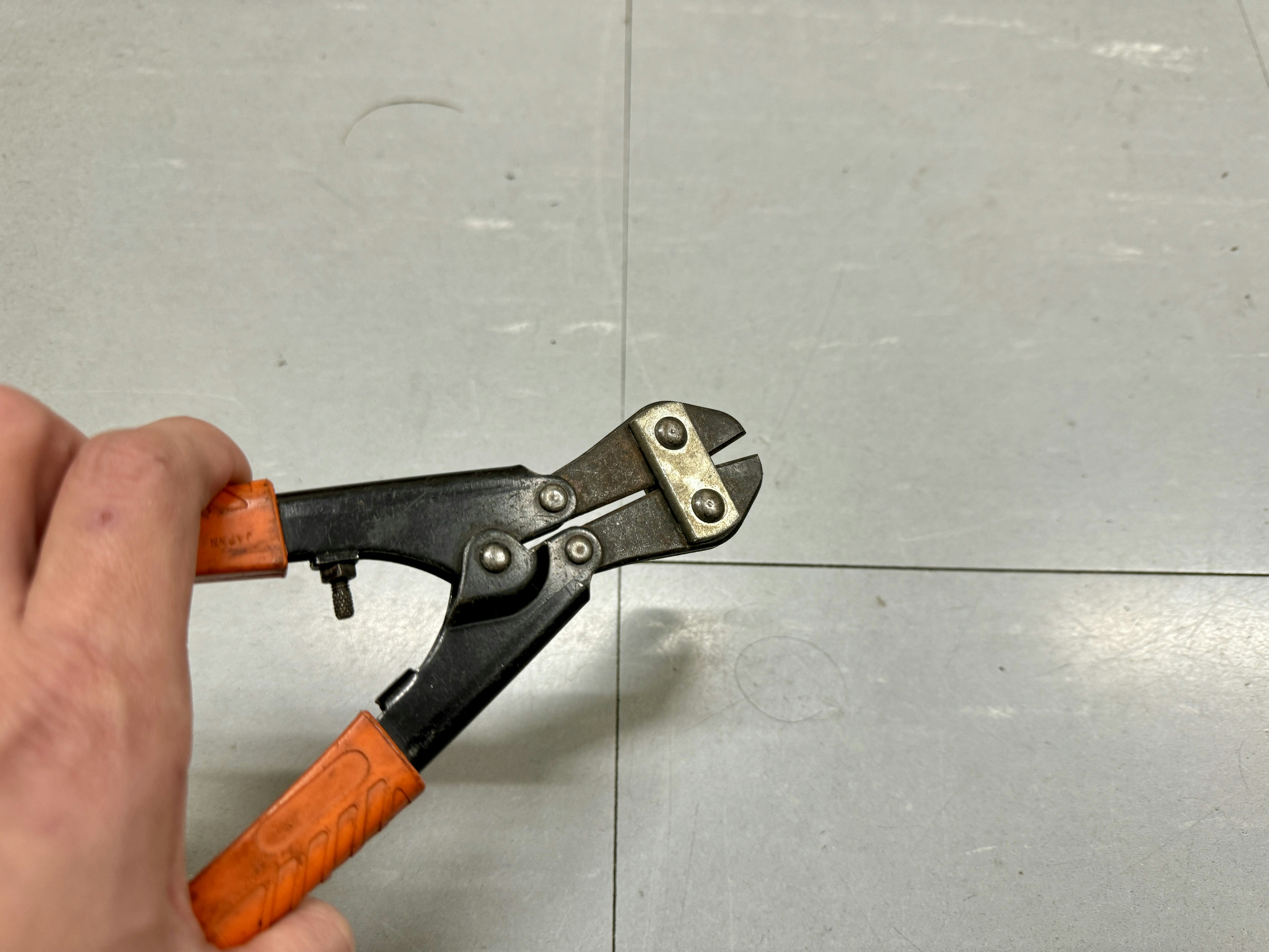 Close-up of a tool with orange handles being held