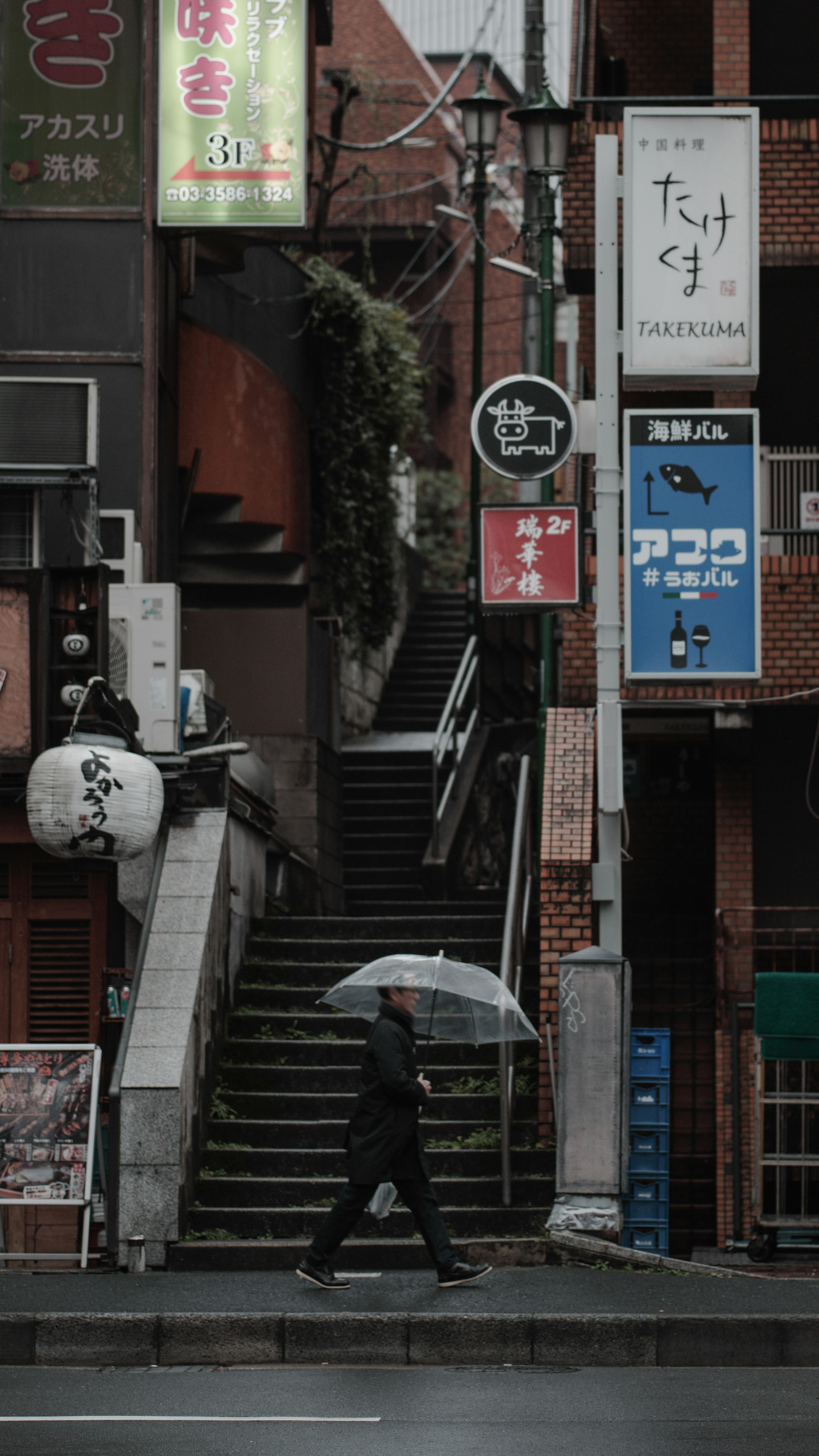 一個人手持雨傘在城市環境中走上樓梯