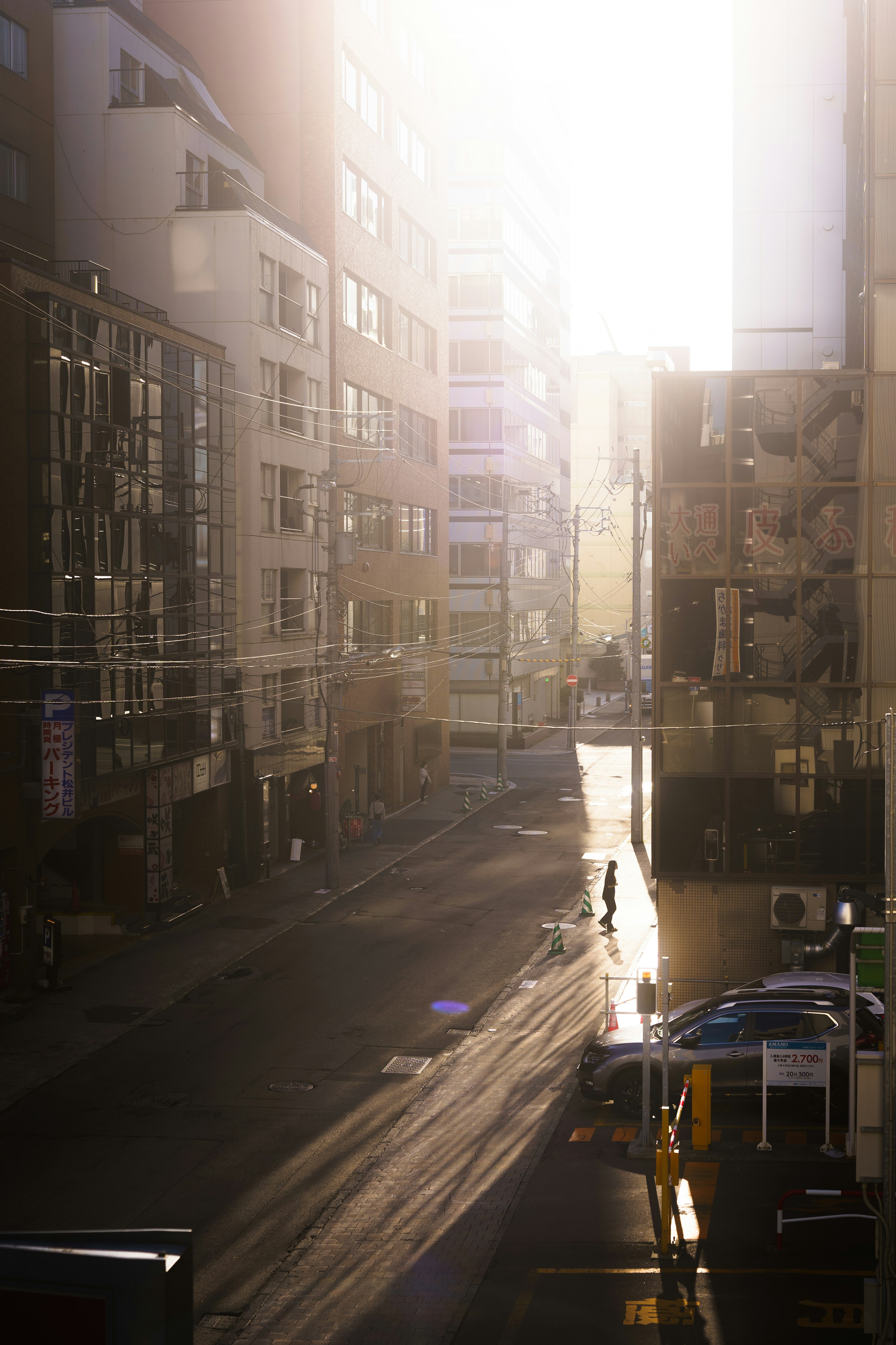 A silhouette of a person standing on a bright street with high-rise buildings