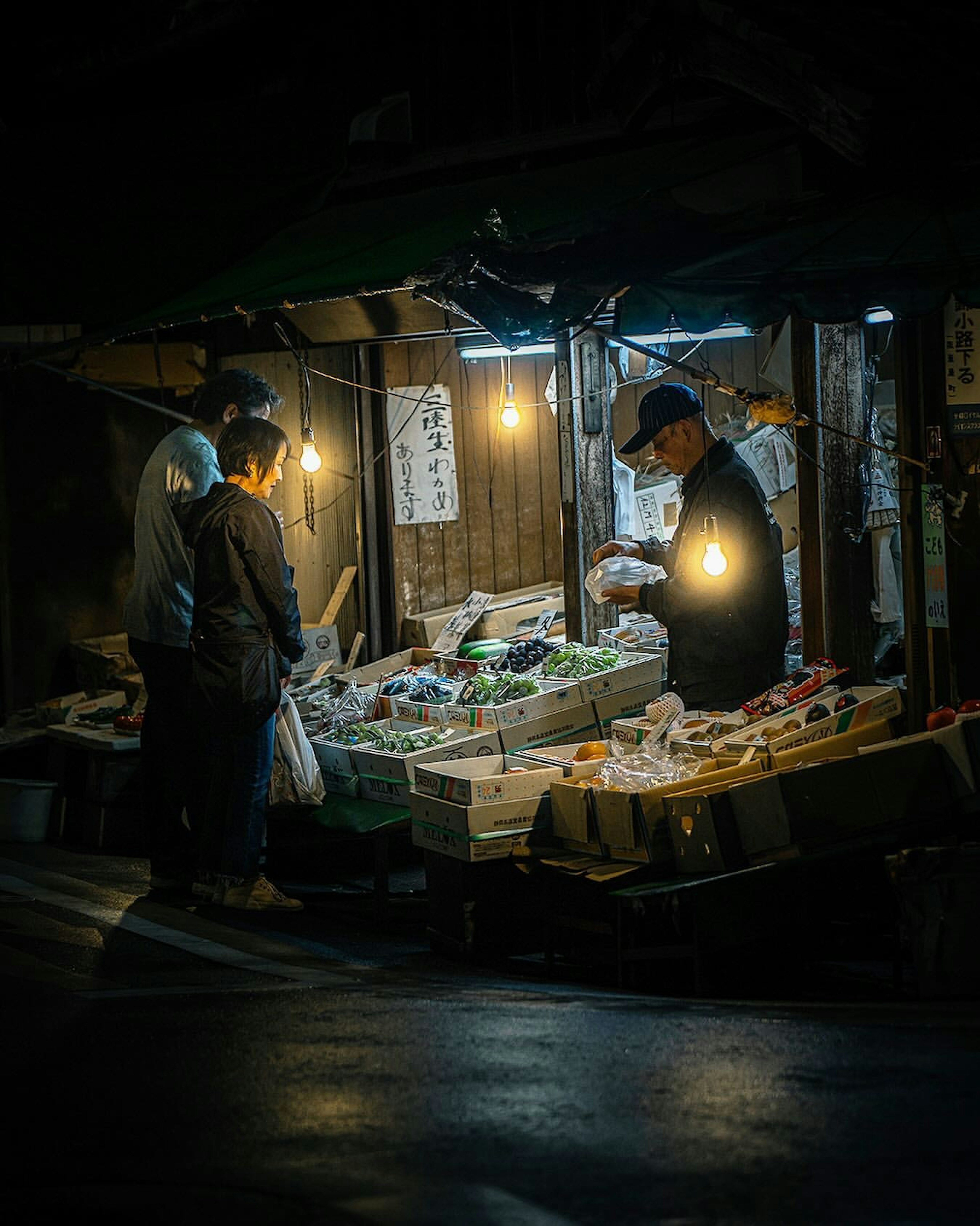 夜市で野菜を選ぶ人々 暖かい光が照らす屋台