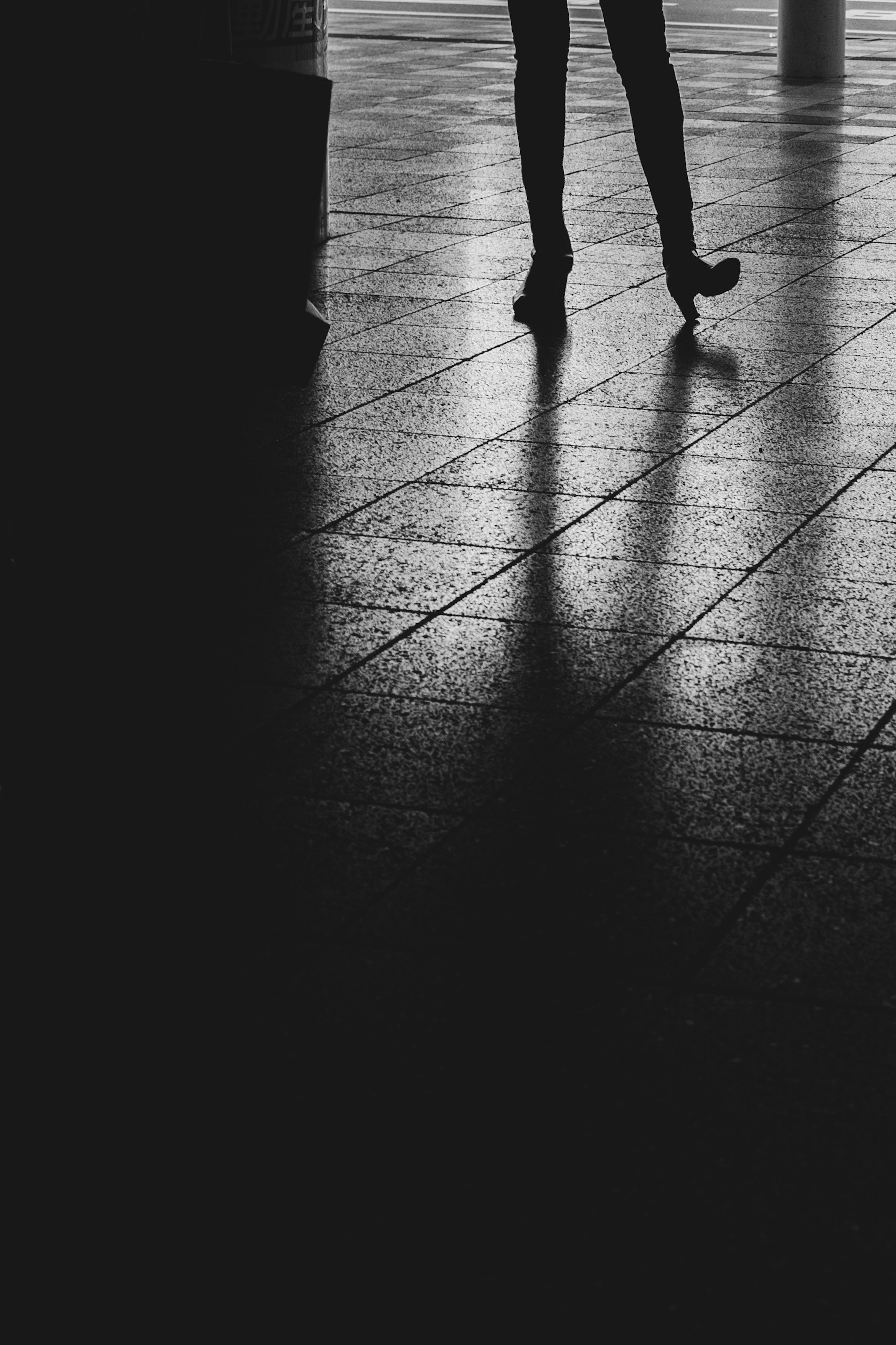 Silhouette de jambes en talons hauts sur une surface réfléchissante