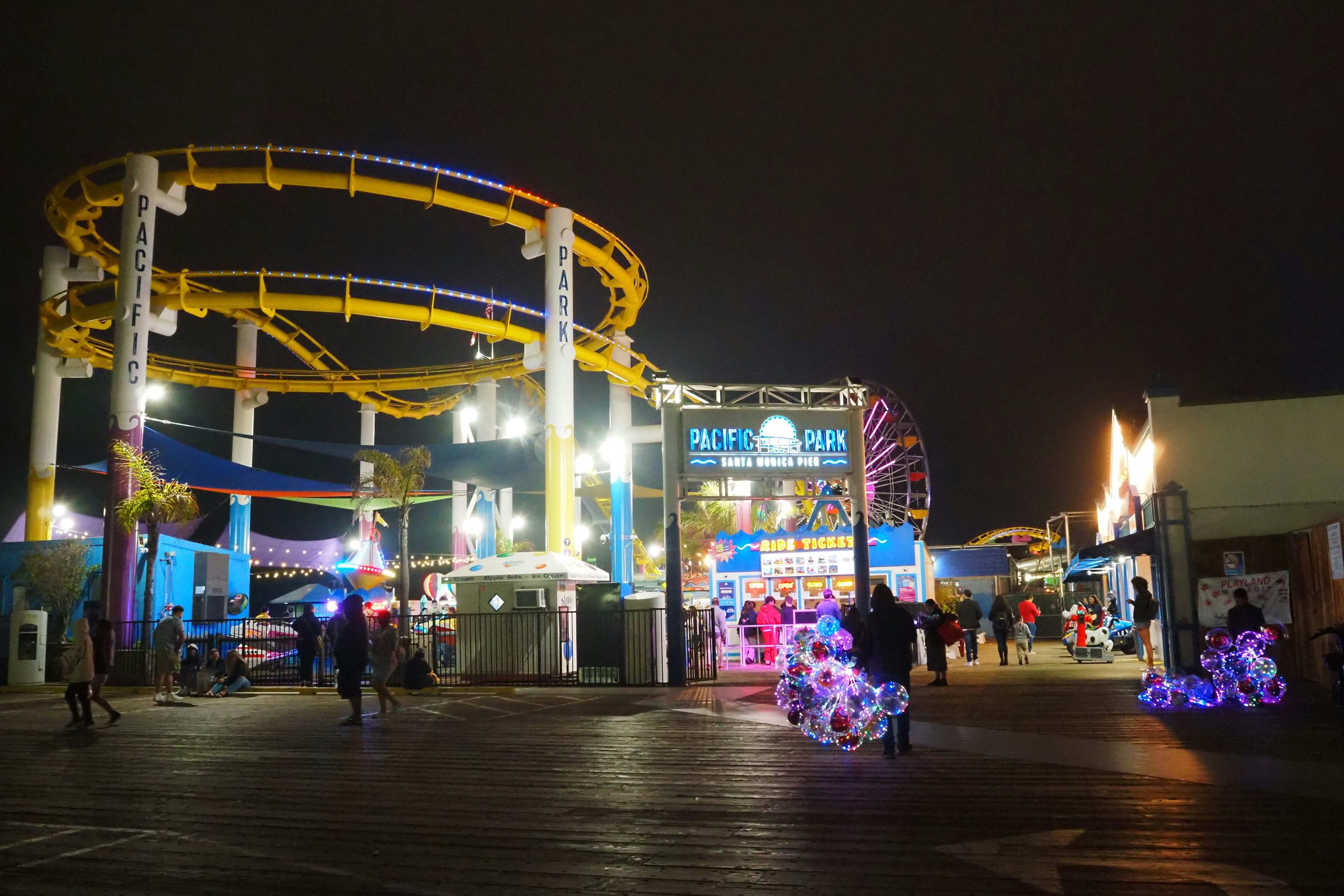 Night view of an amusement park featuring a roller coaster and ferris wheel