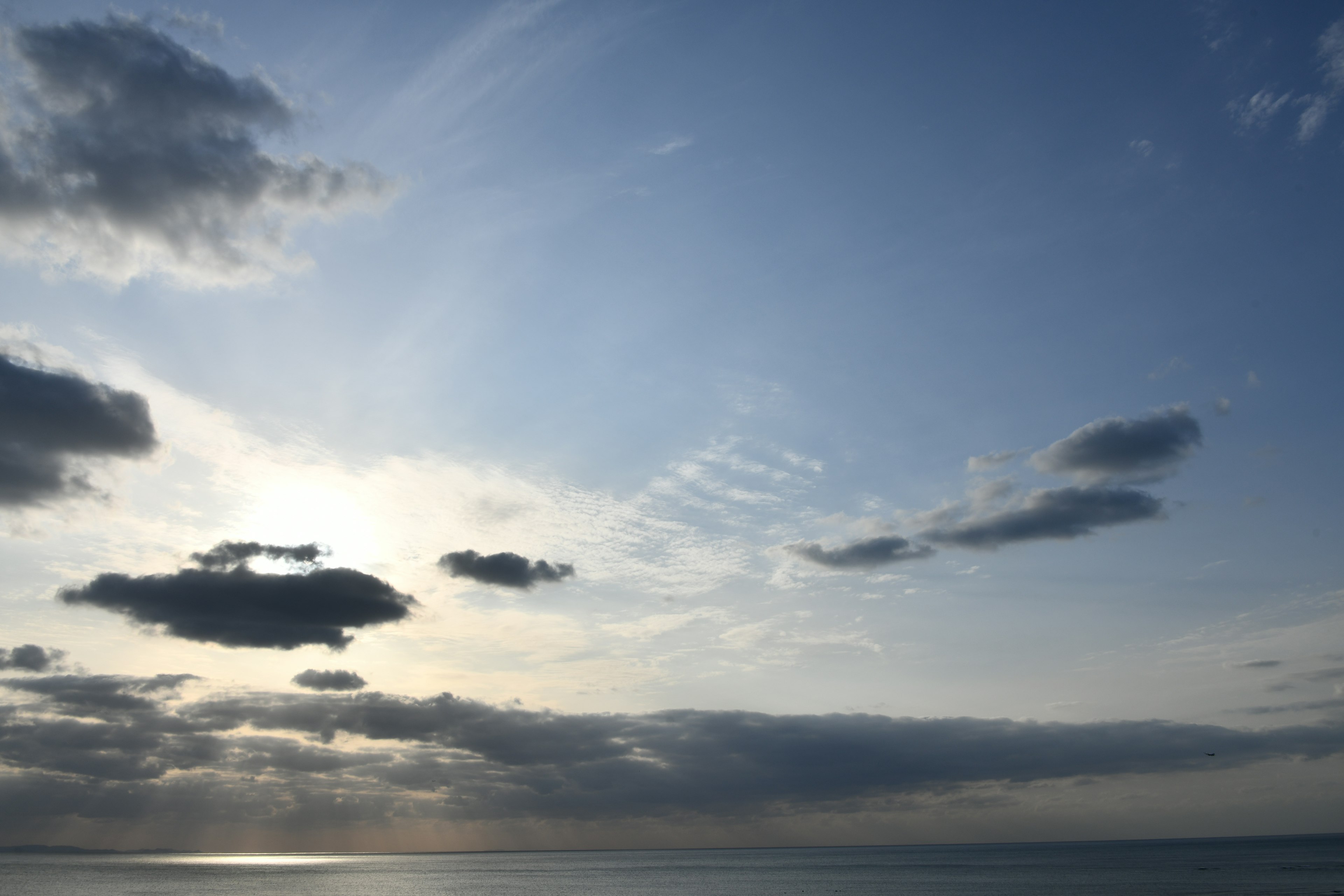 Ciel bleu avec des nuages et coucher de soleil se reflétant sur la mer