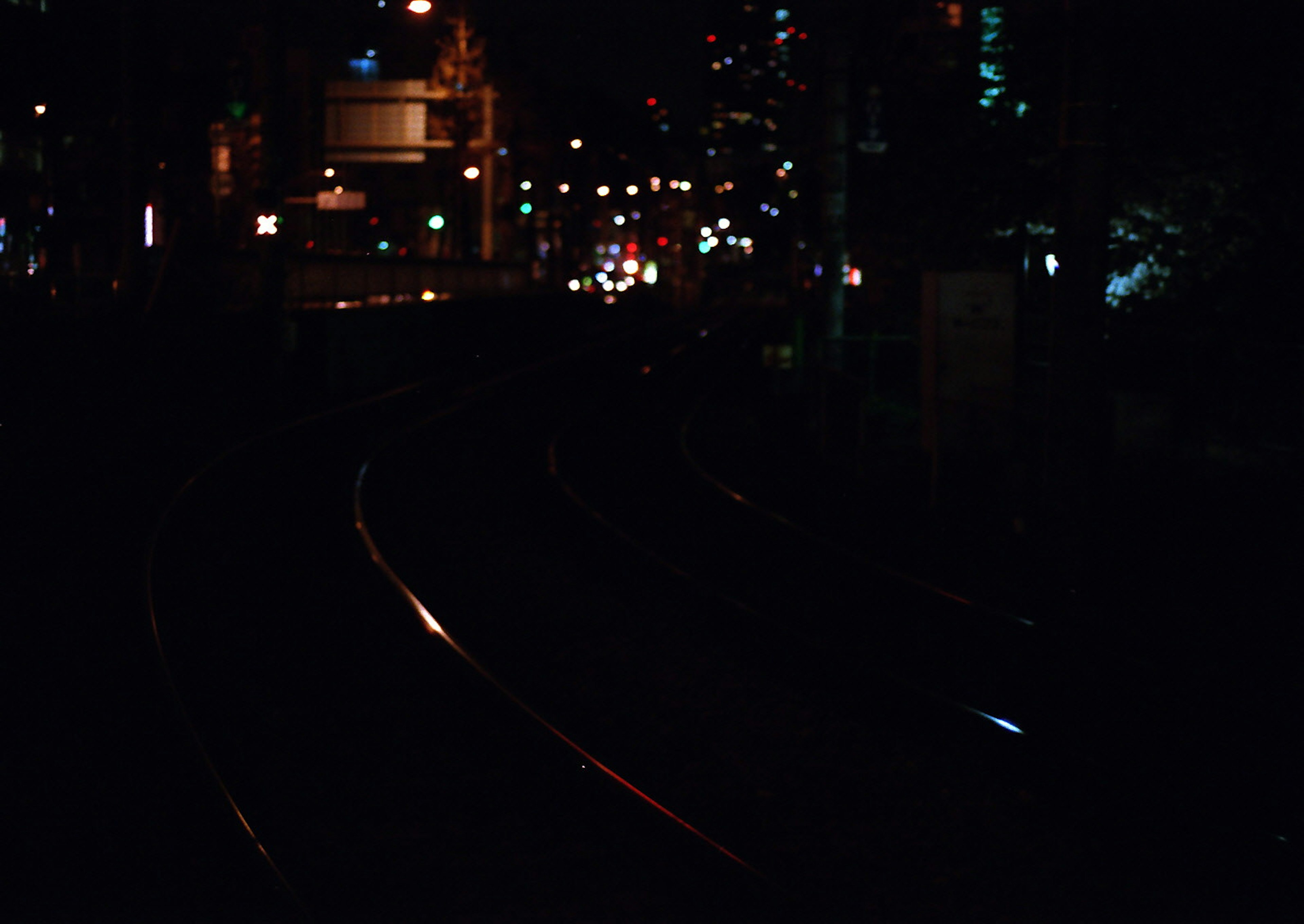 Vías de tren urbanas oscuras iluminadas por luces de la ciudad