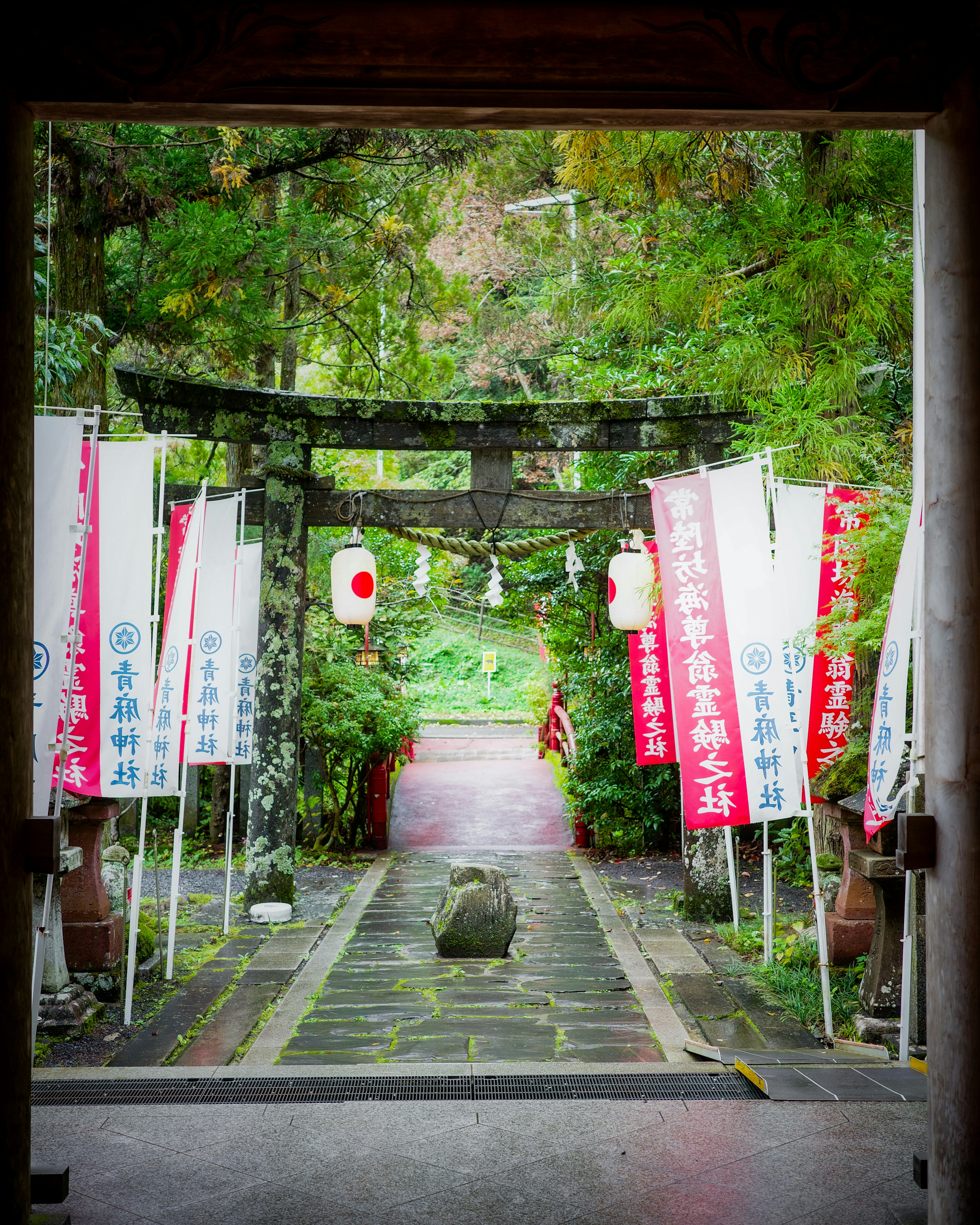 通往郁郁蔥蔥花園的鳥居和日本旗幟的景色