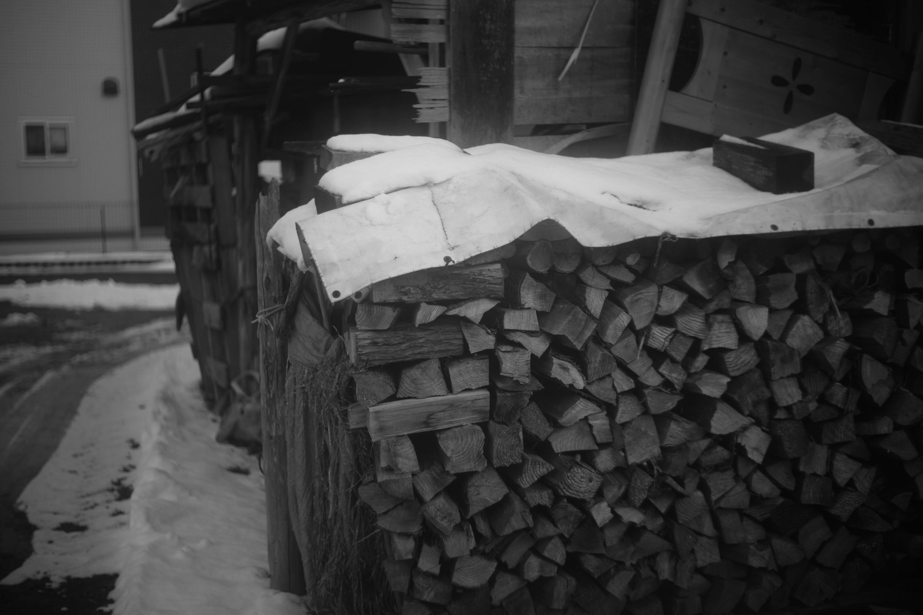 Stack of firewood covered with snow near a wooden shed