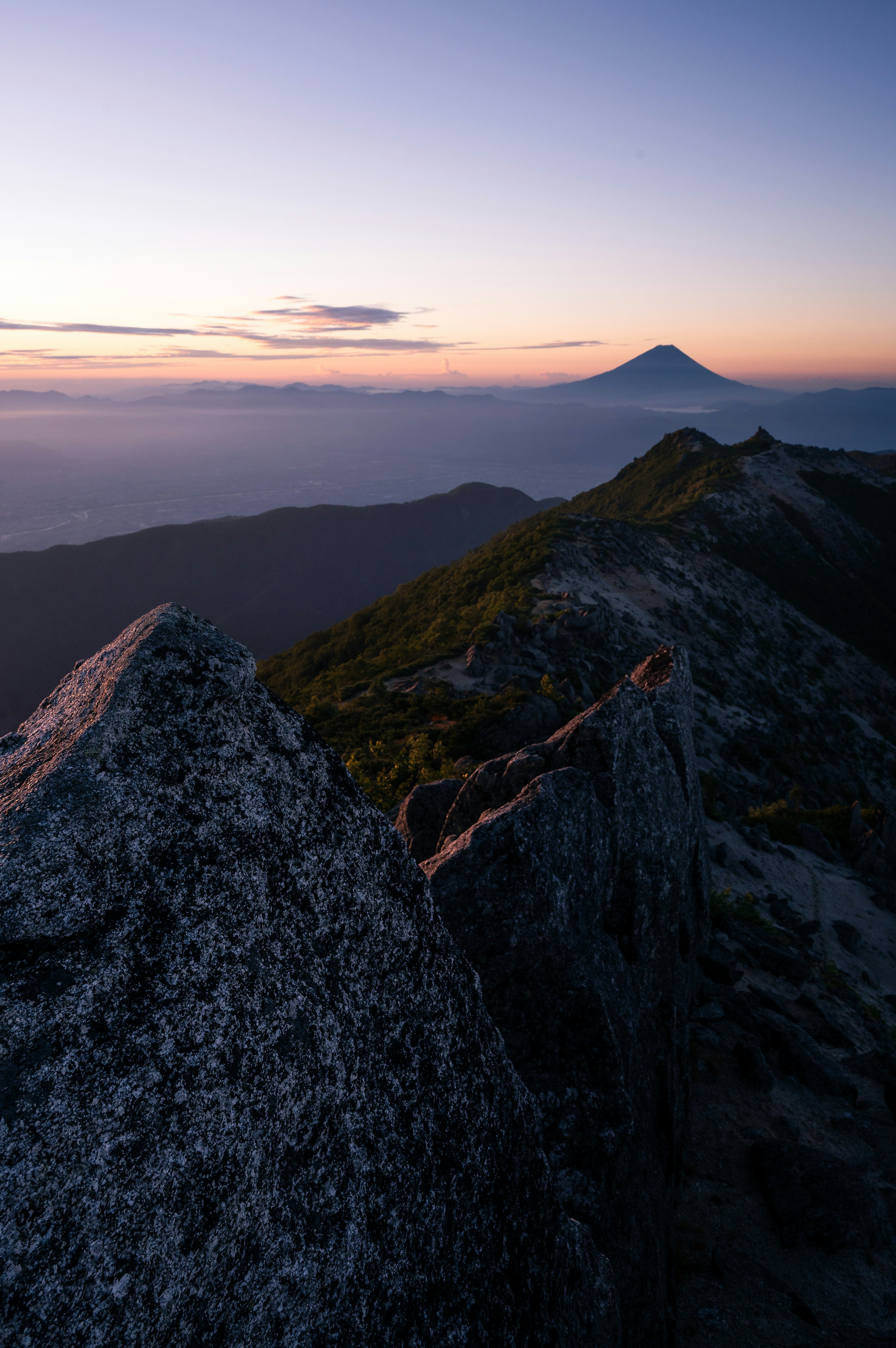 夕日を背景にした山の風景 大きな岩と遠くに見える火山