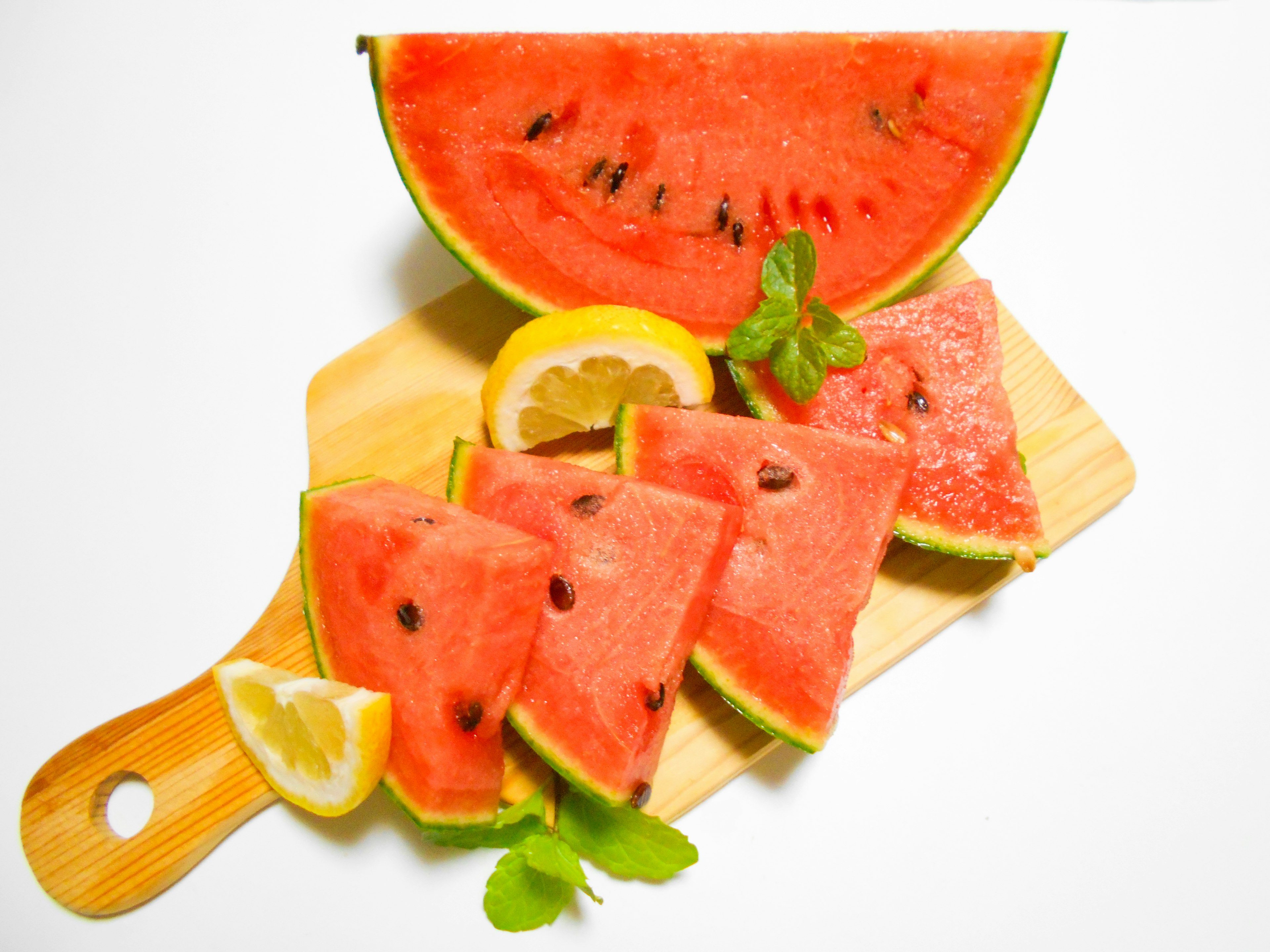 Slices of watermelon and lemon on a wooden cutting board