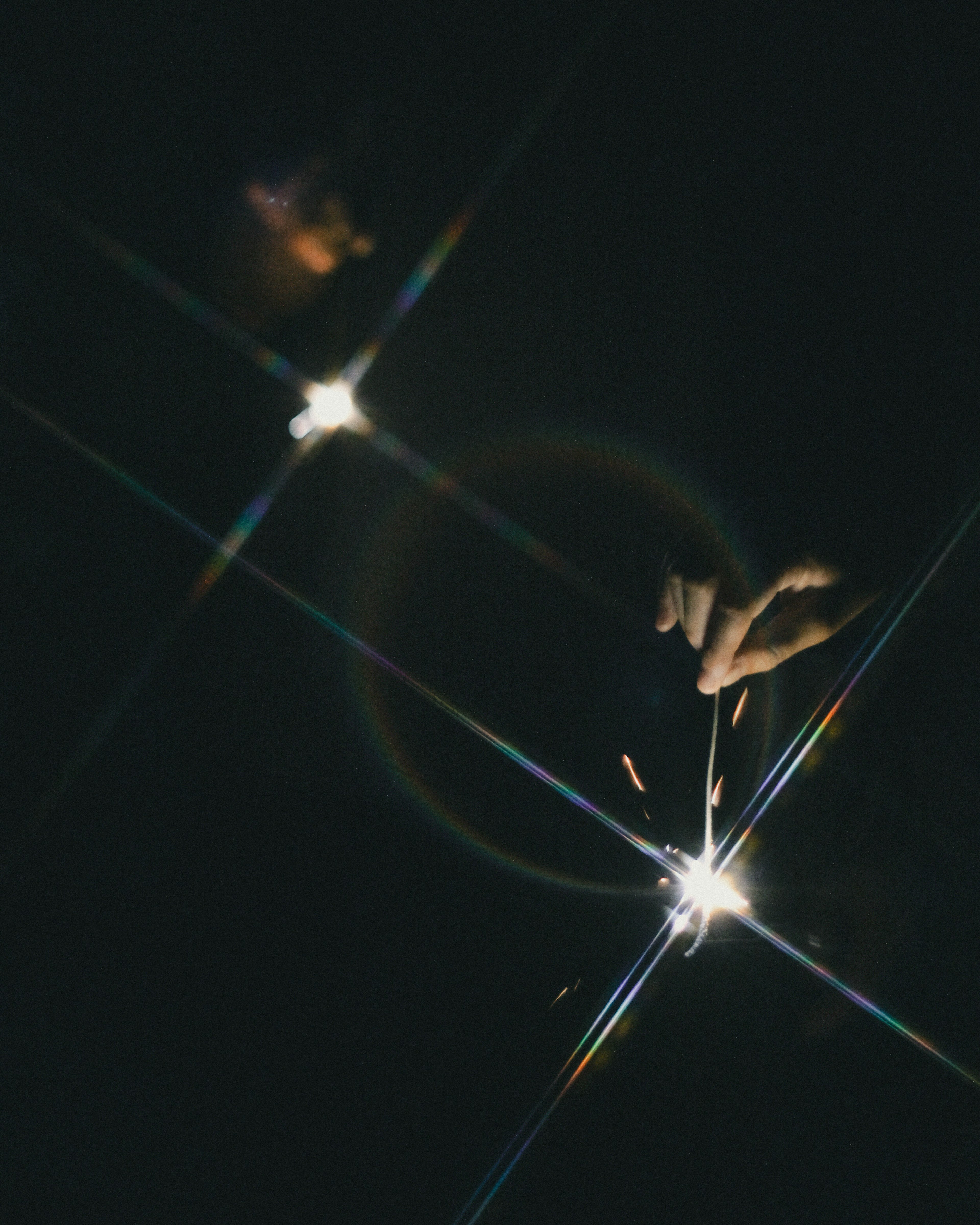 Hands holding sparklers with bright lights against a dark background