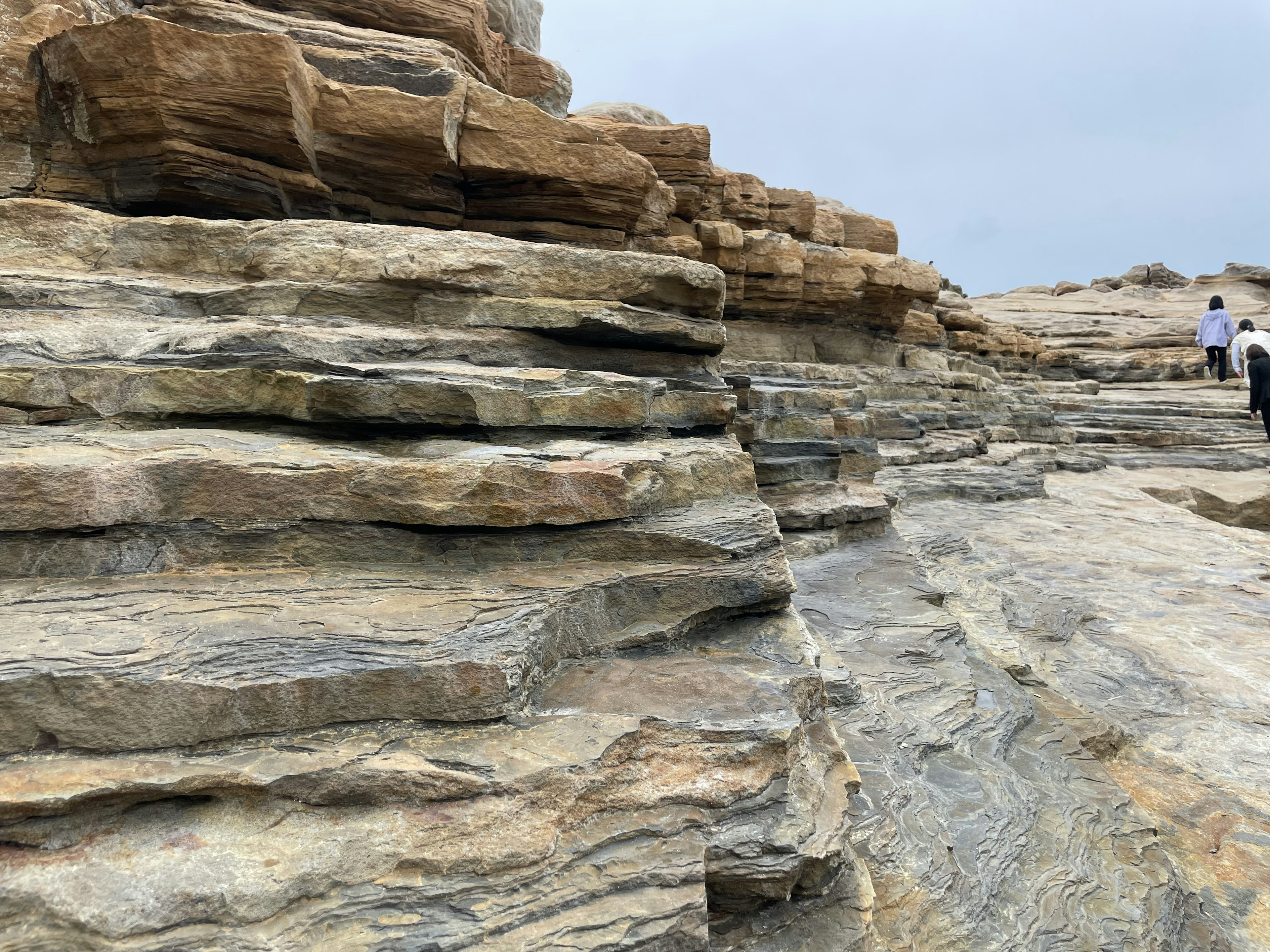 Formazioni rocciose stratificate con persone che camminano