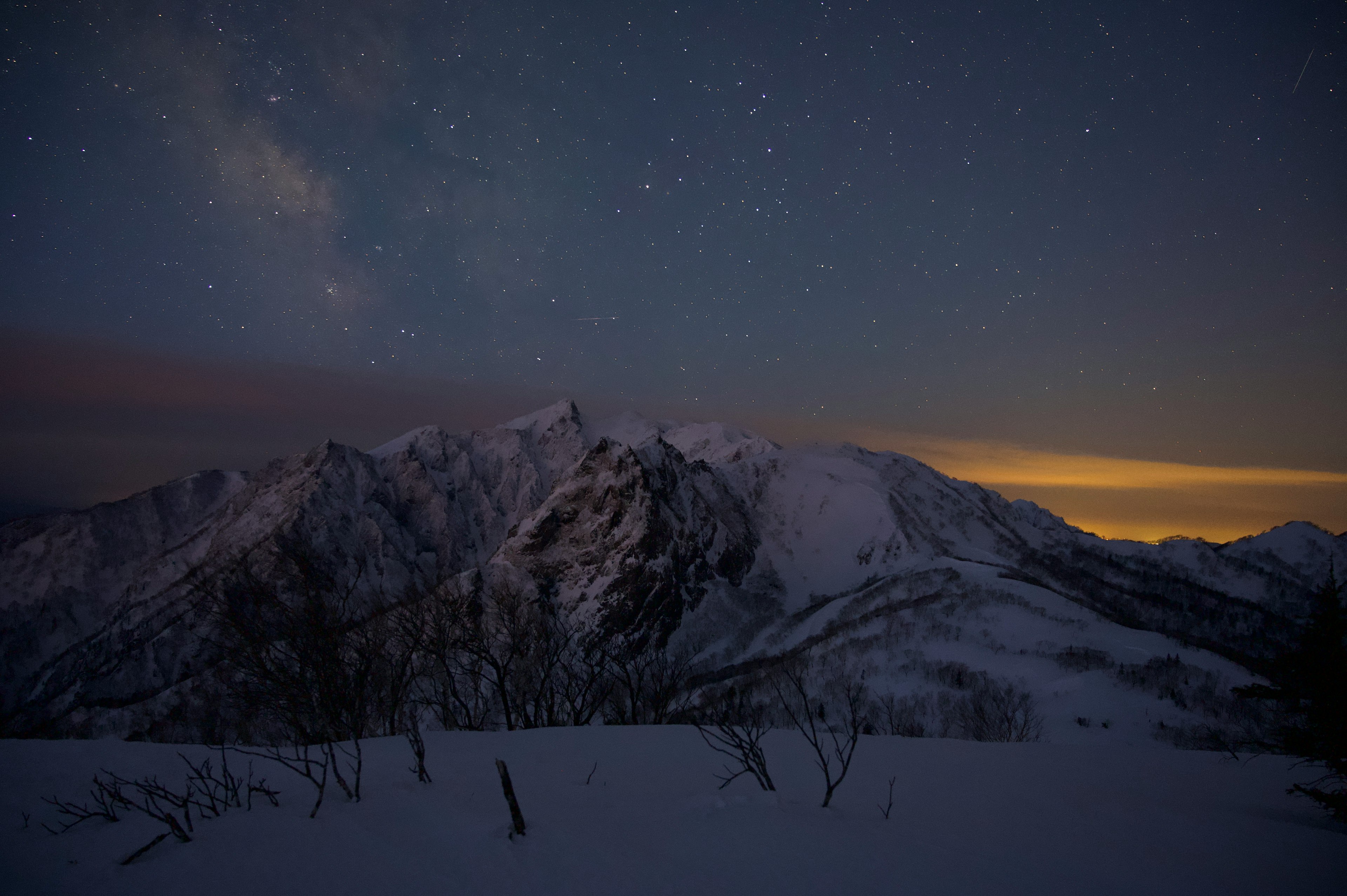 Pemandangan malam dengan gunung bersalju dan langit berbintang