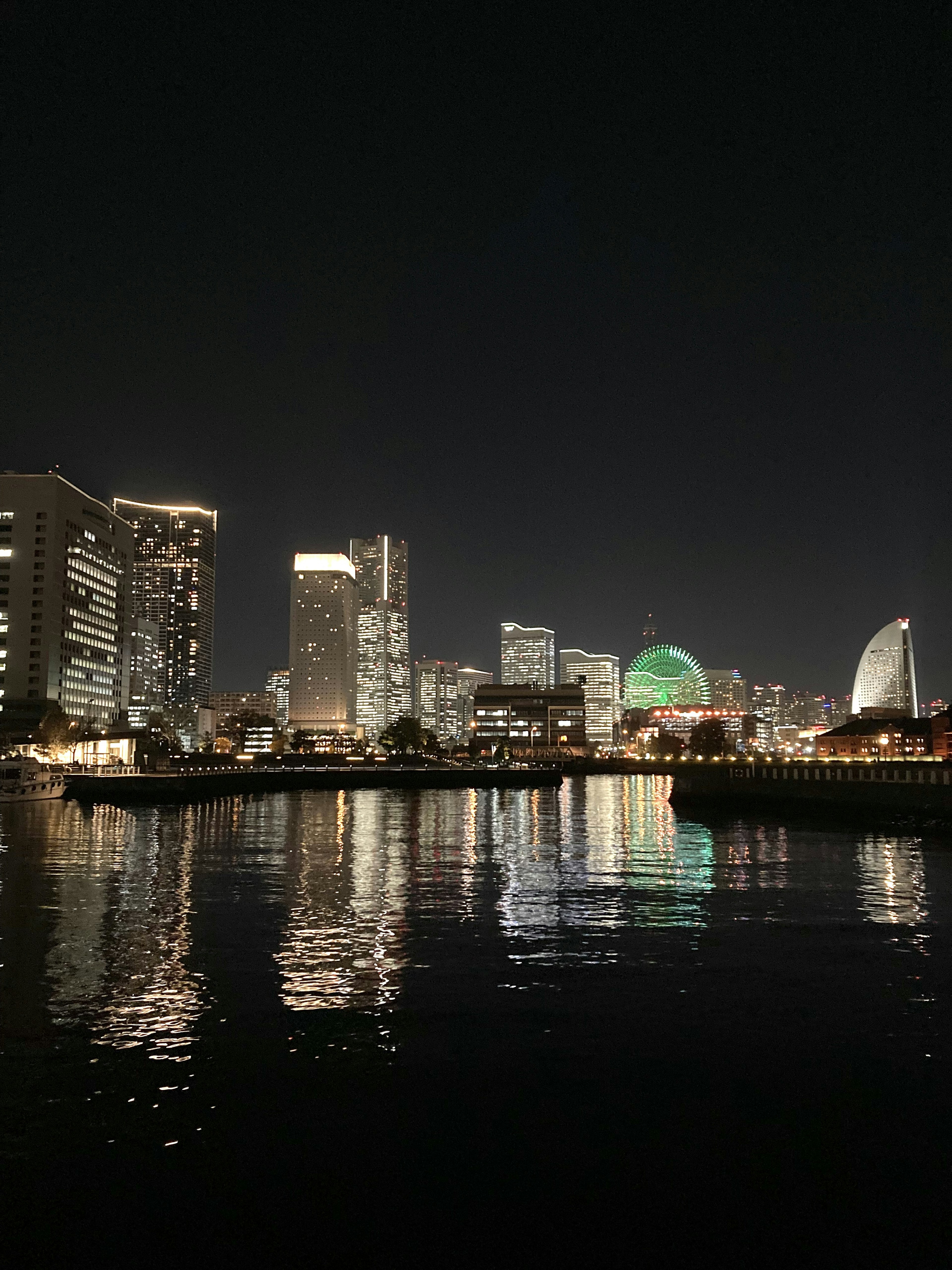 Vista nocturna de rascacielos a lo largo del río con reflejos en el agua