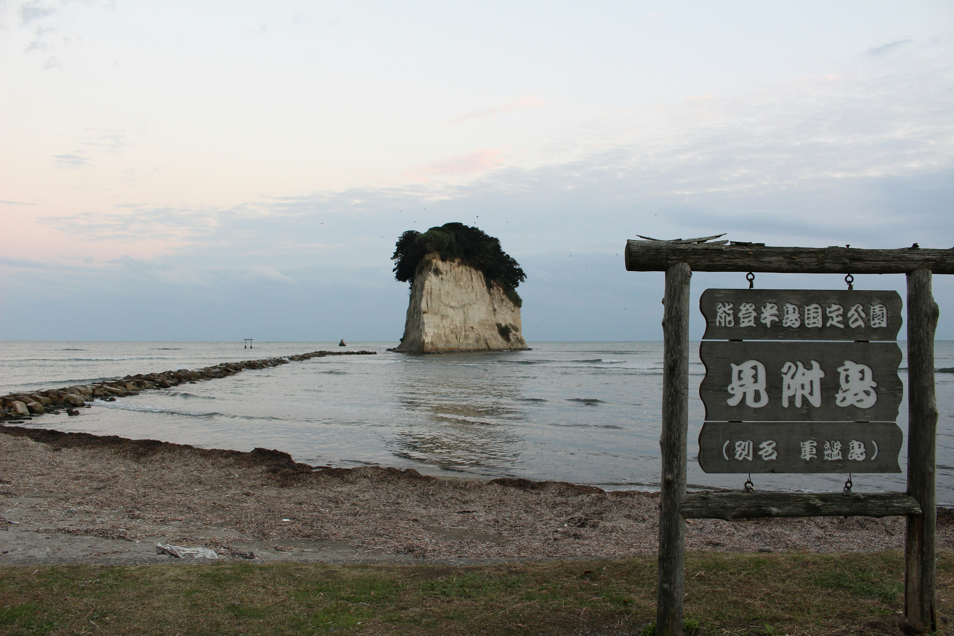 A rocky island in the sea with a sign in the foreground