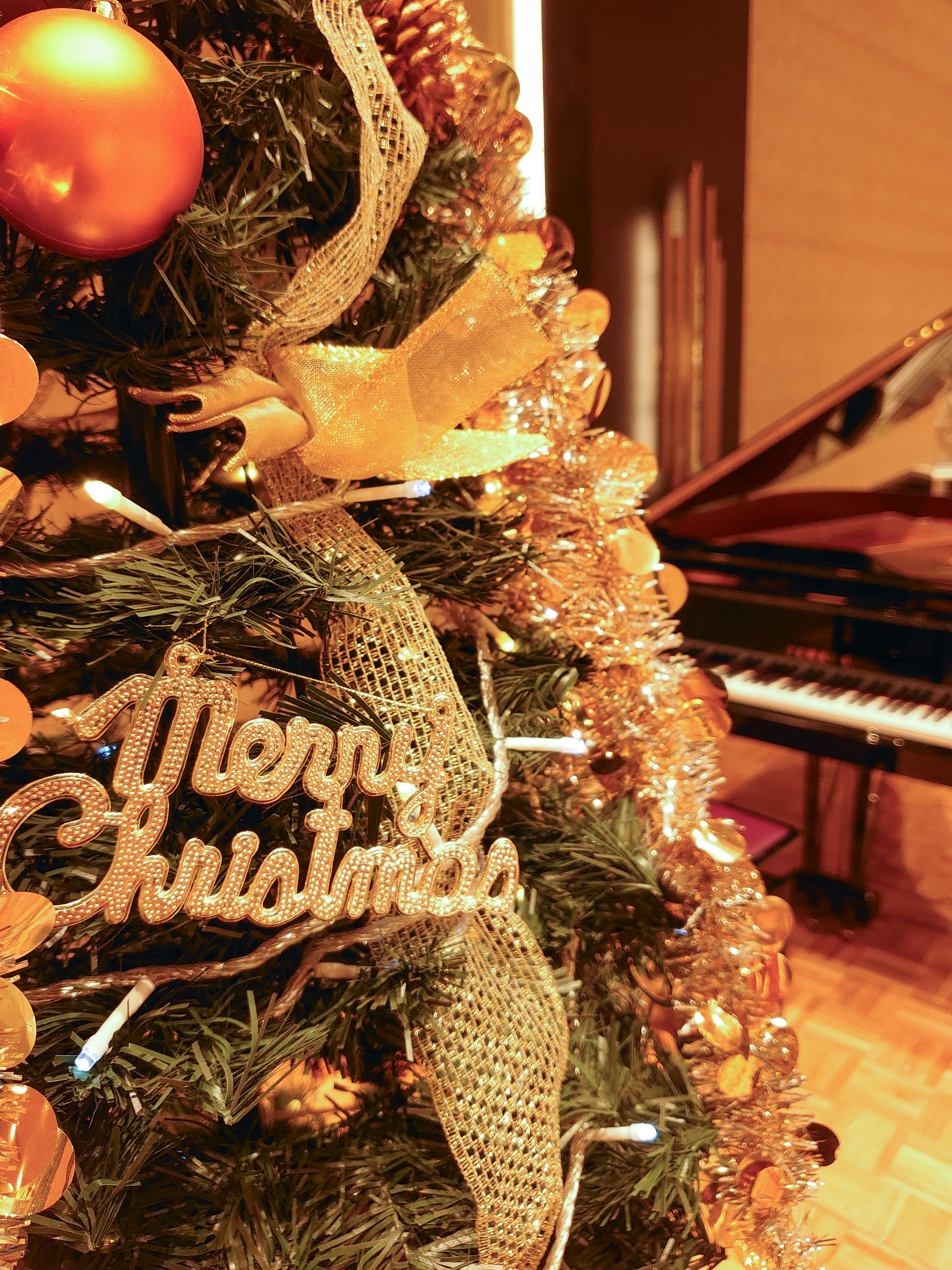 Christmas tree adorned with ornaments and a grand piano in a cozy room