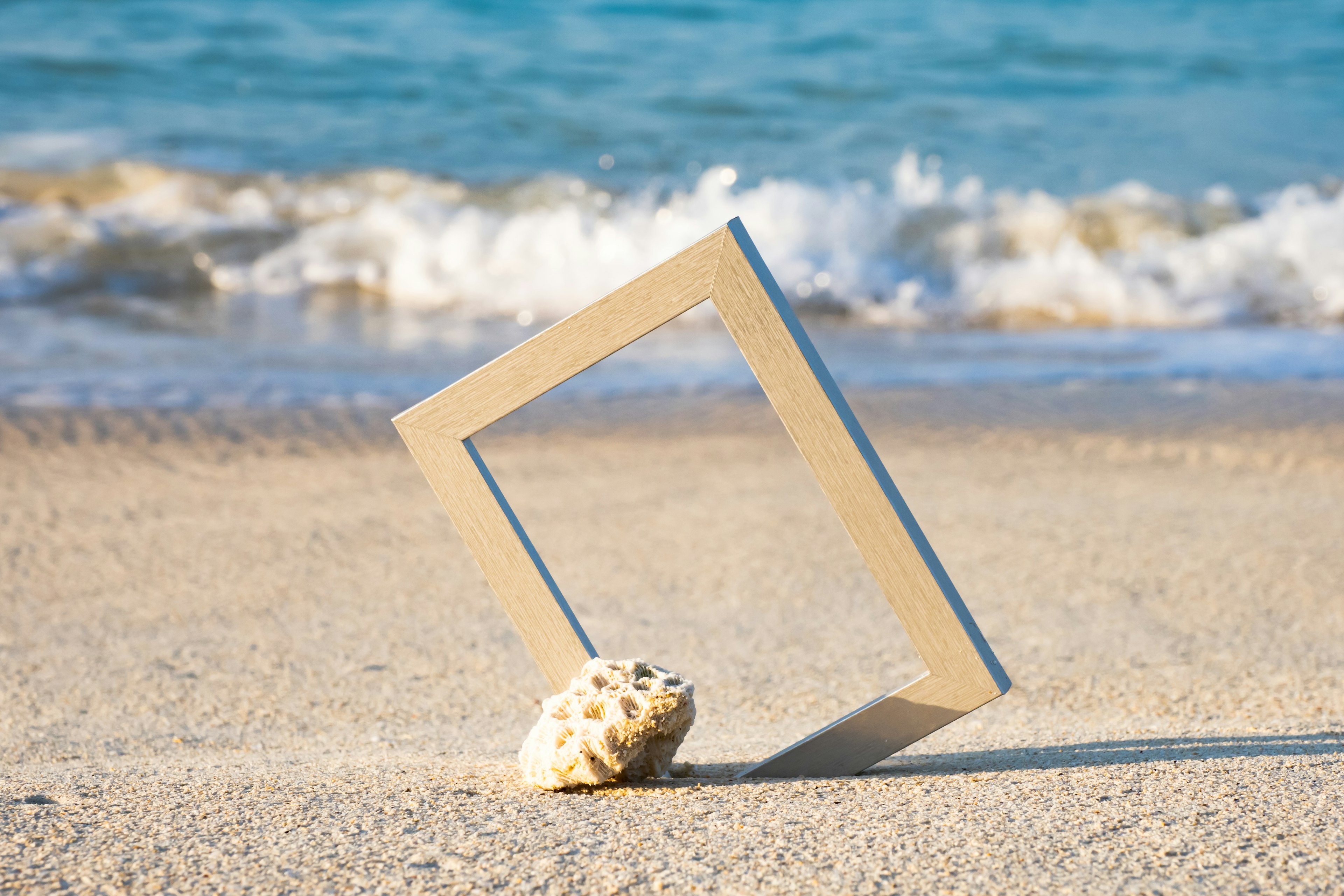 Una scena di spiaggia con un telaio in piedi e una conchiglia sulla sabbia con onde oceaniche sullo sfondo