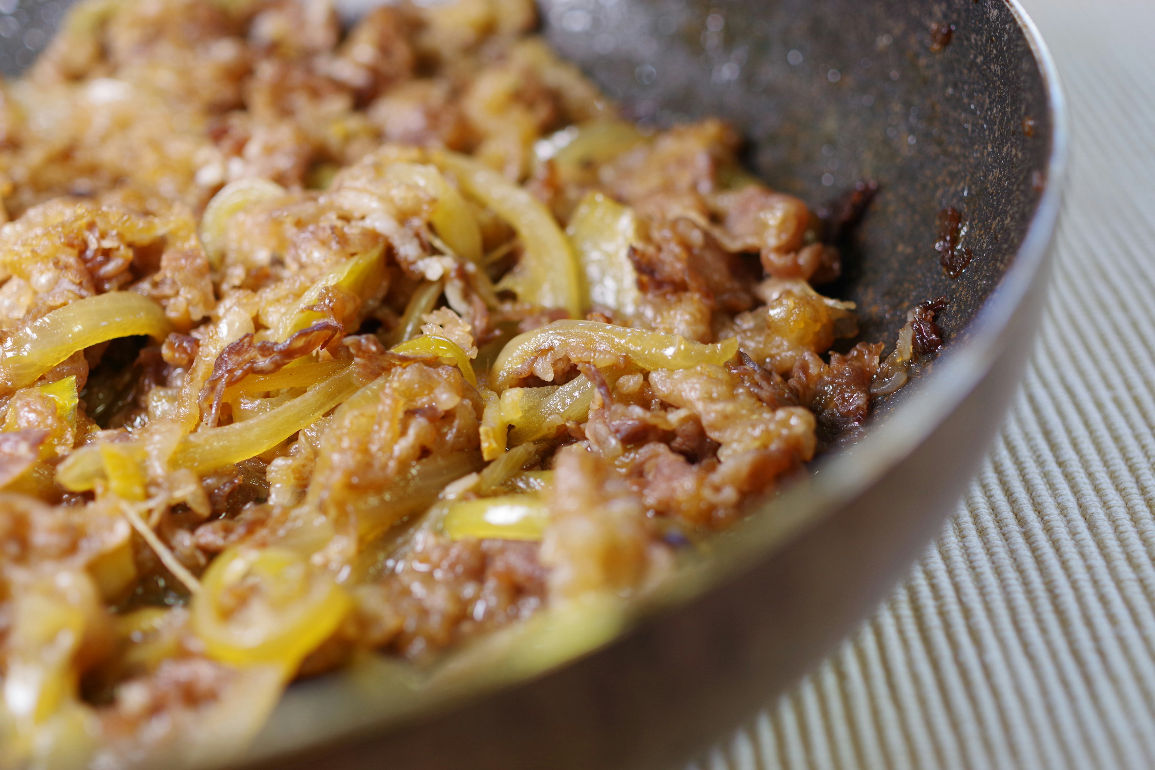 Eine Pfanne mit einem Gericht aus gekochtem Schweinefleisch und Zwiebeln