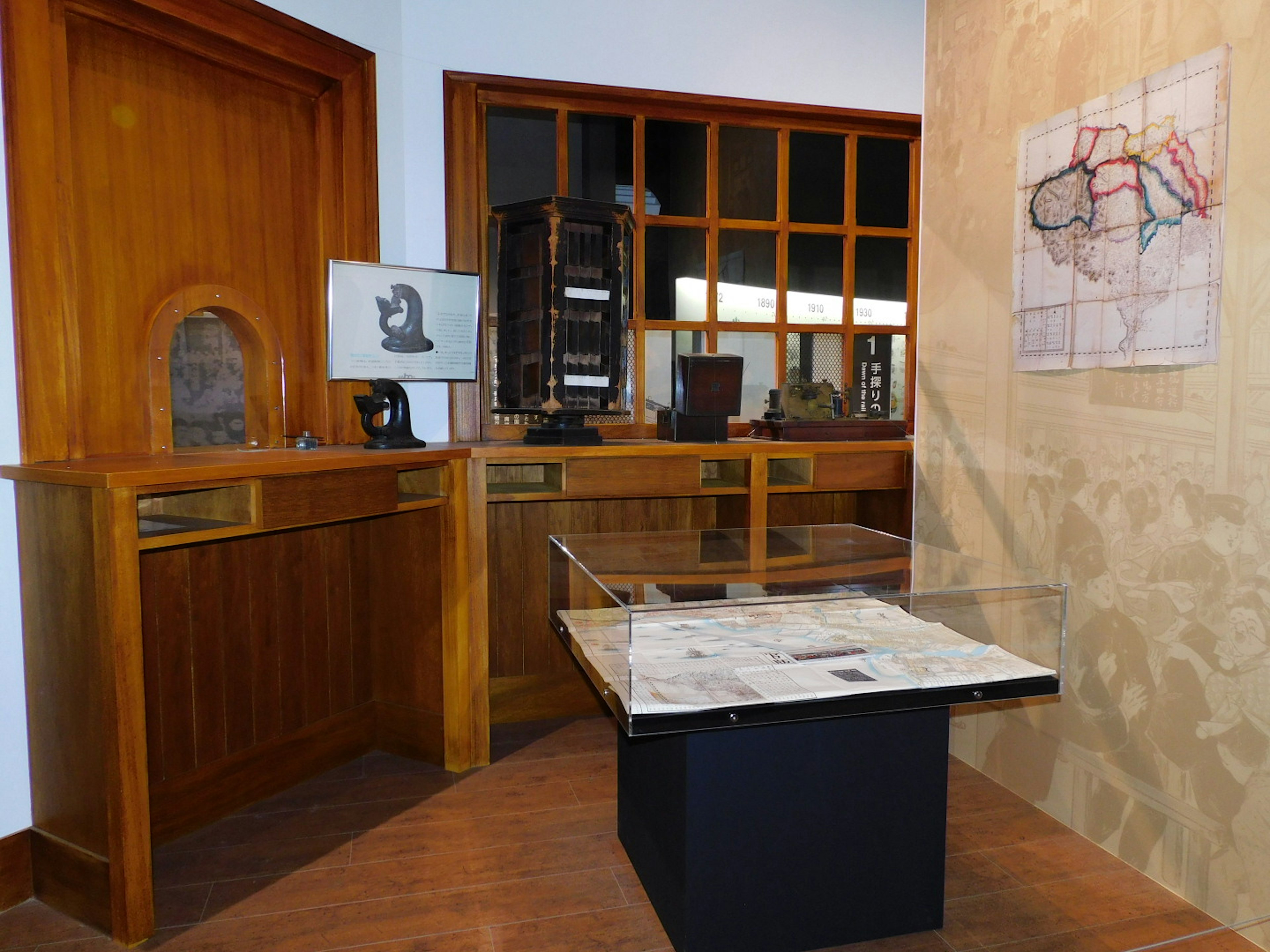 Interior de una sala de exhibición con vitrinas de madera y un mapa en la pared