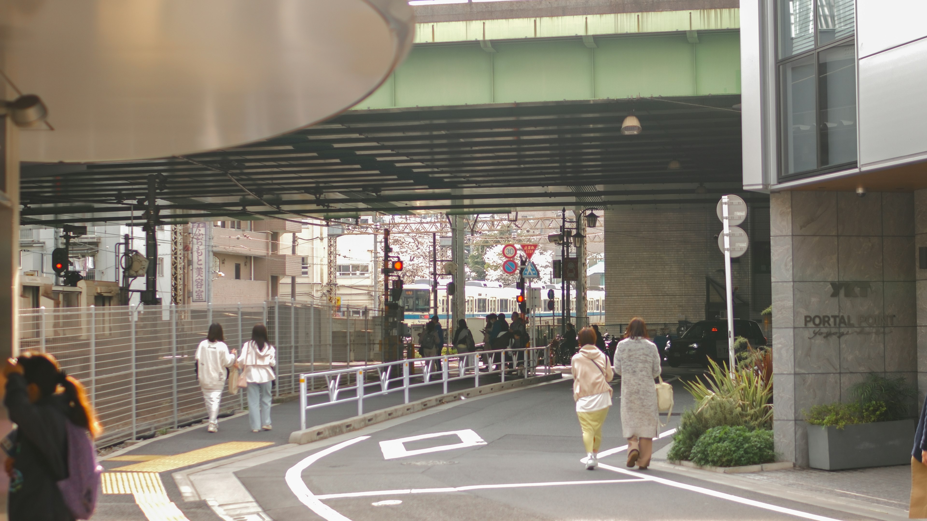 人々が行き交う都市の風景 緑の橋の下にある歩道