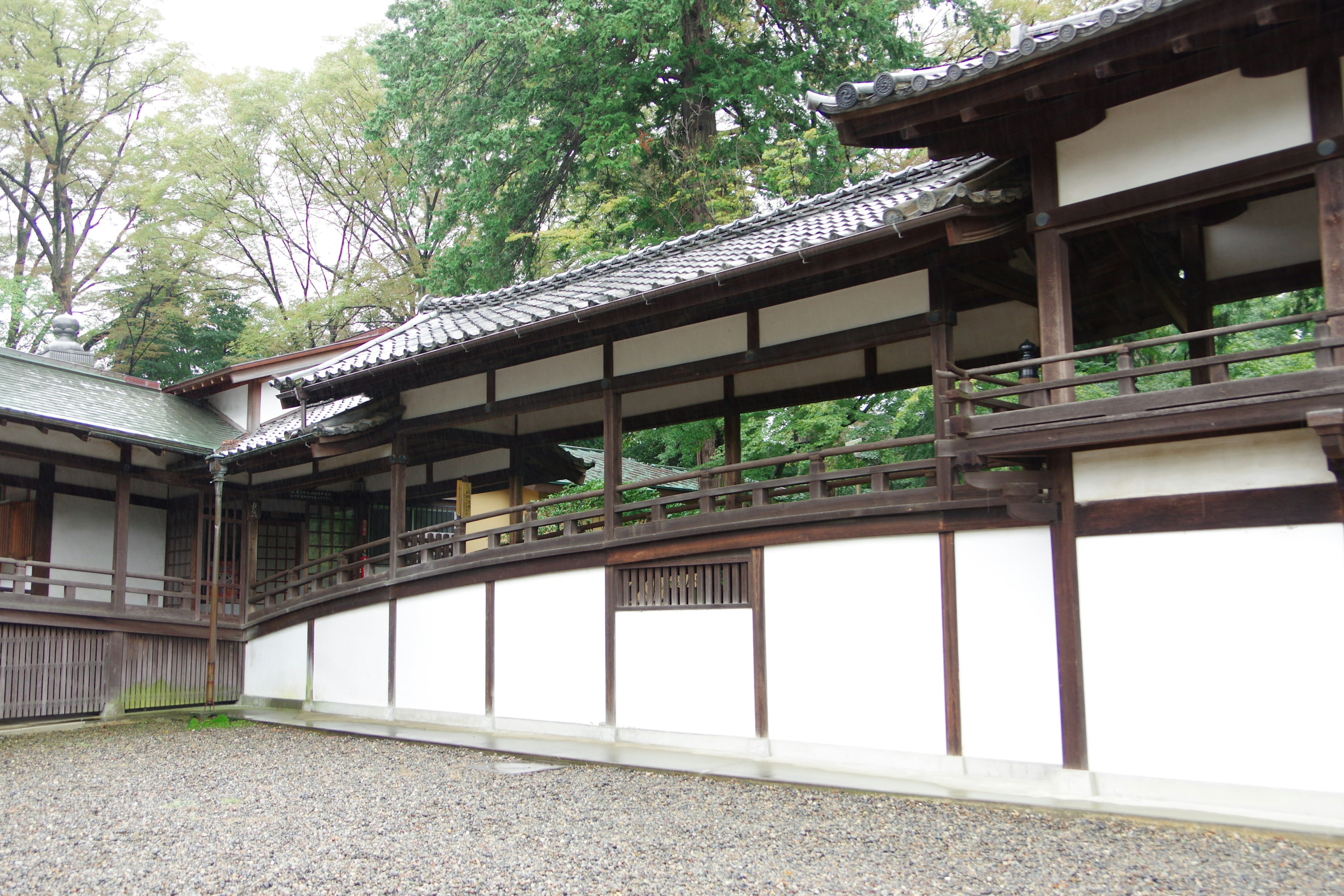 Traditional Japanese architectural landscape with a garden featuring white walls and wooden balcony