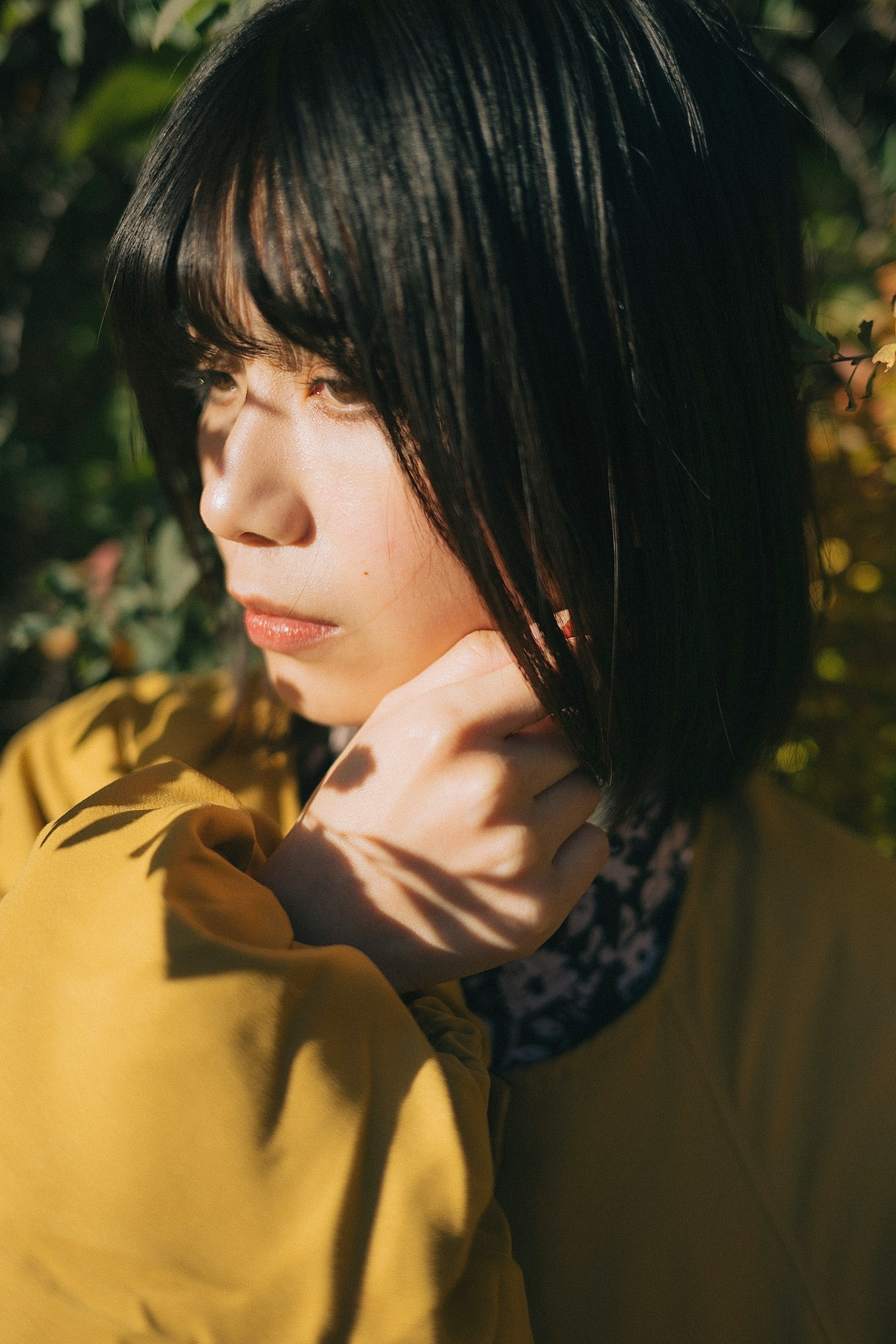 A woman in a yellow coat posing amidst nature