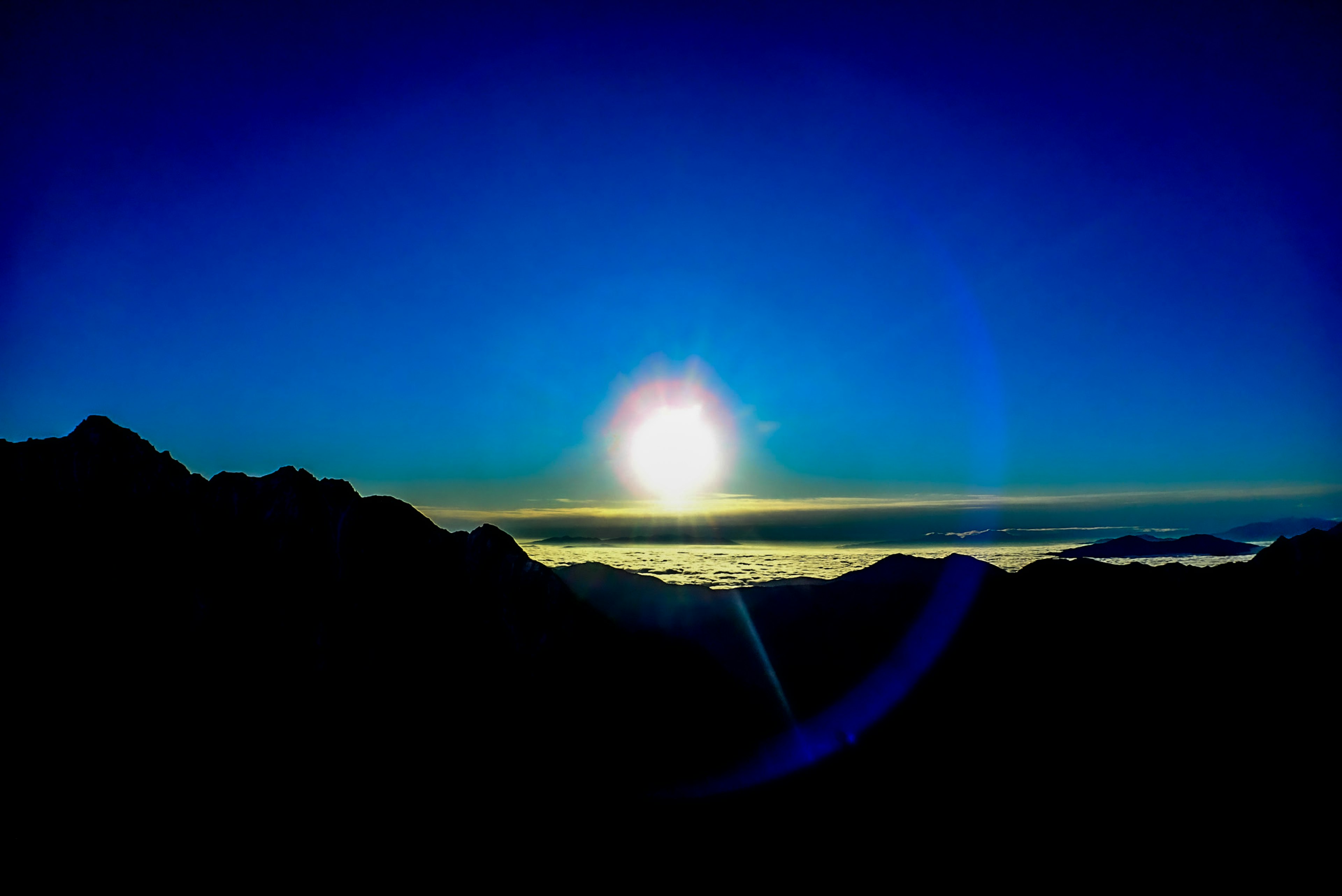 Lever de soleil sur des montagnes en silhouette avec un ciel bleu