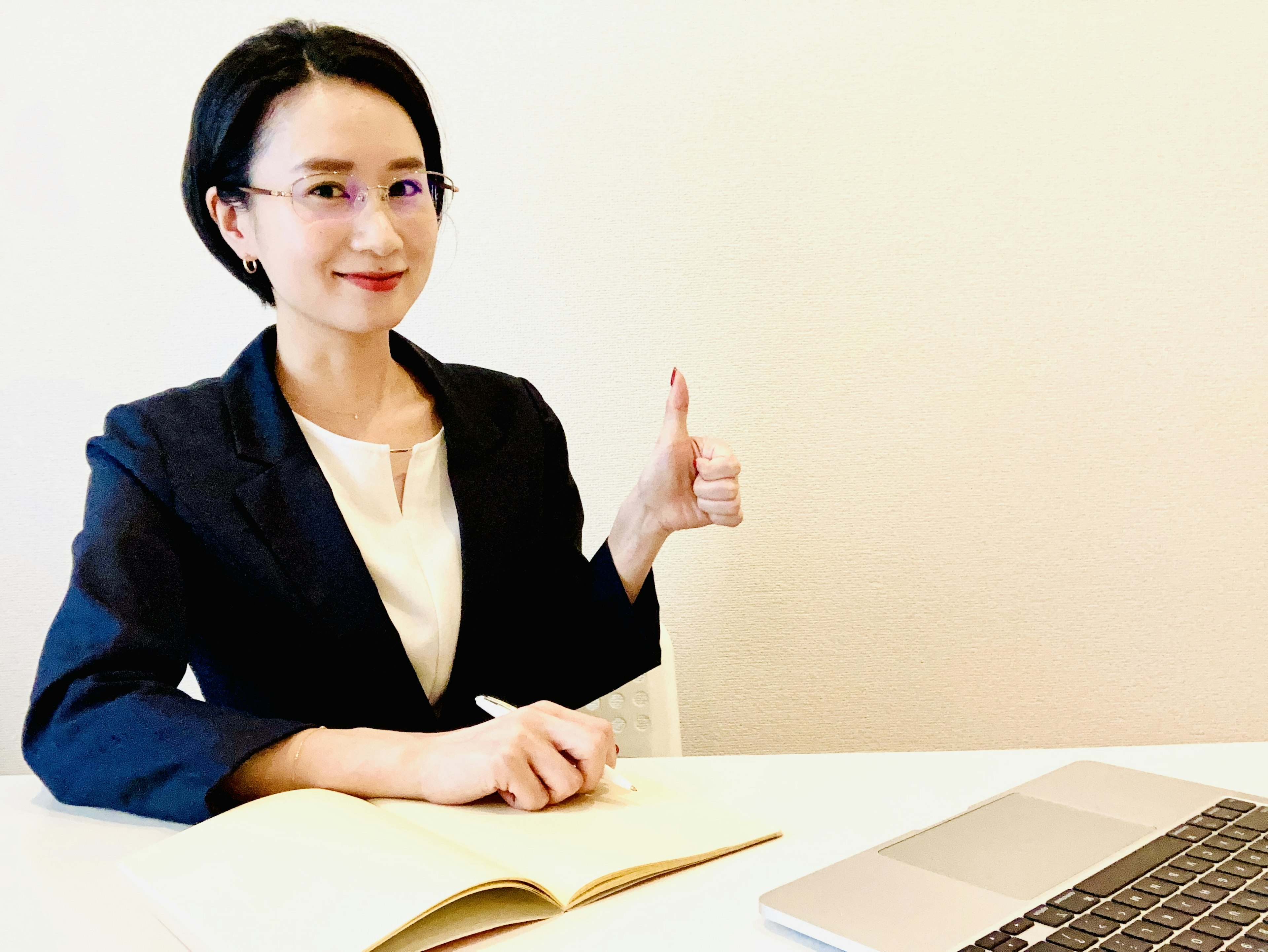 정장 차림의 여성이 미소를 지으며 엄지손가락을 치켜세우고 있다