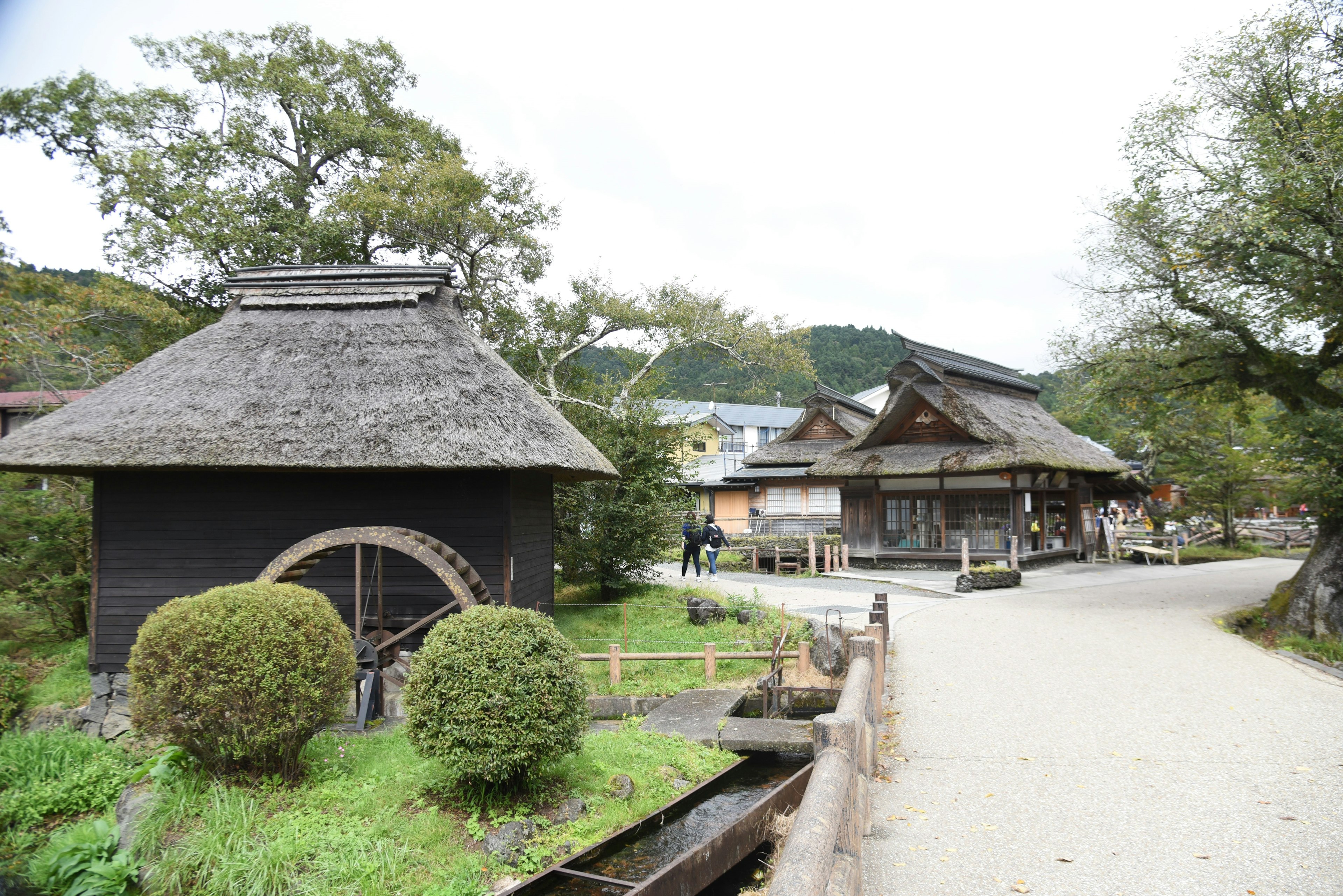 Traditional Japanese village scene featuring a water wheel and wooden houses