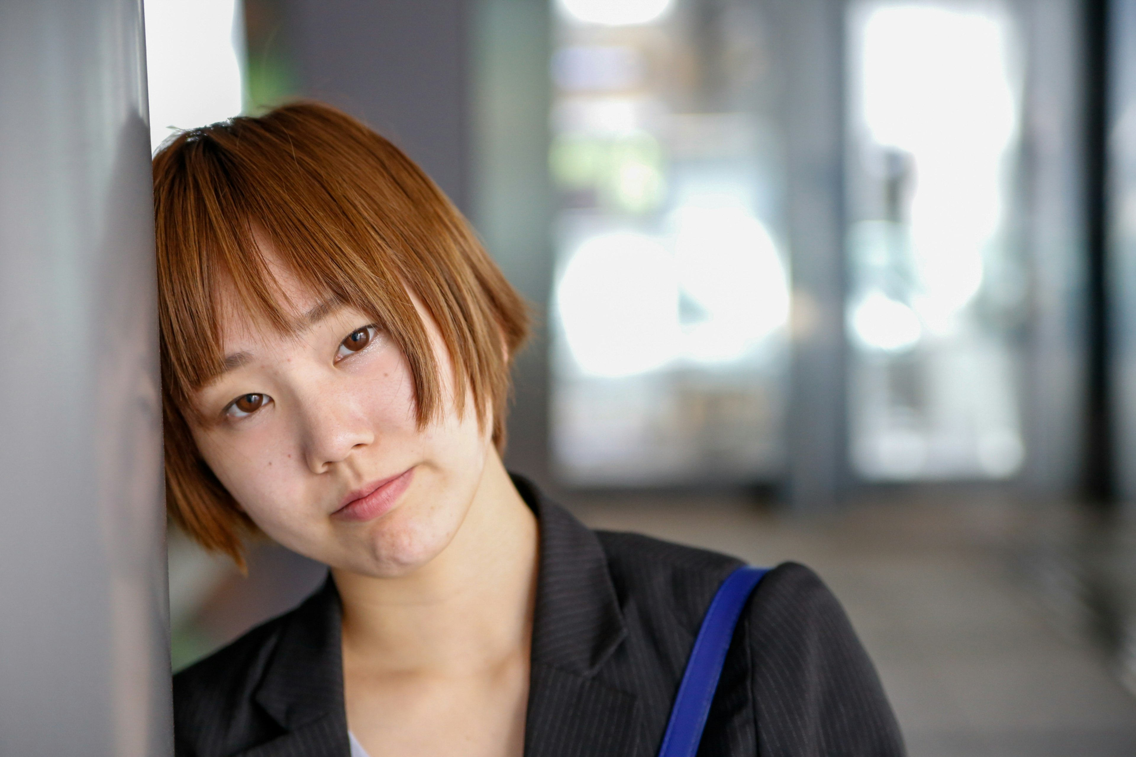 Jeune femme appuyée contre un mur avec une expression pensive