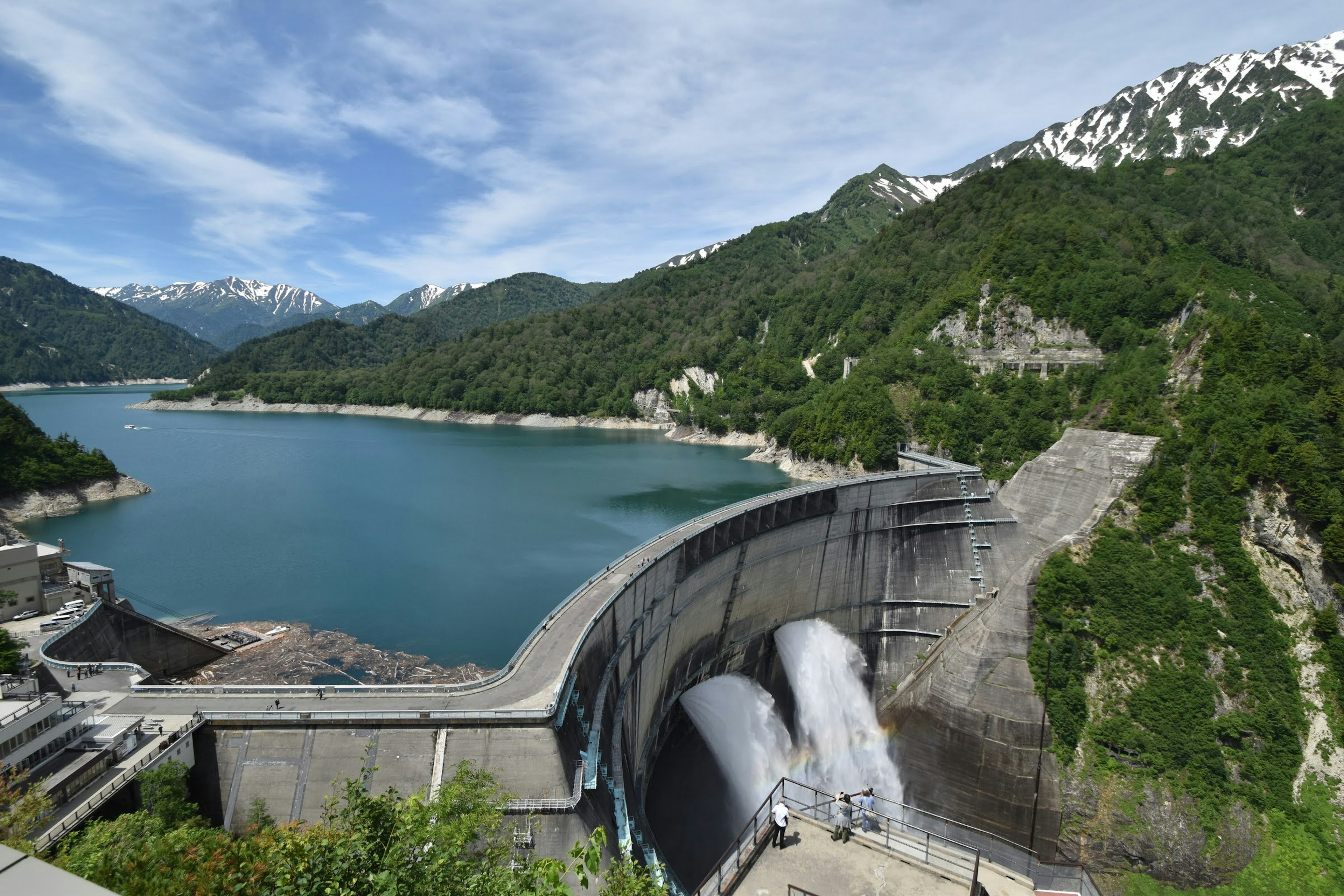 Vista panoramica di una diga circondata da montagne e un lago Acqua che scorre dalla diga