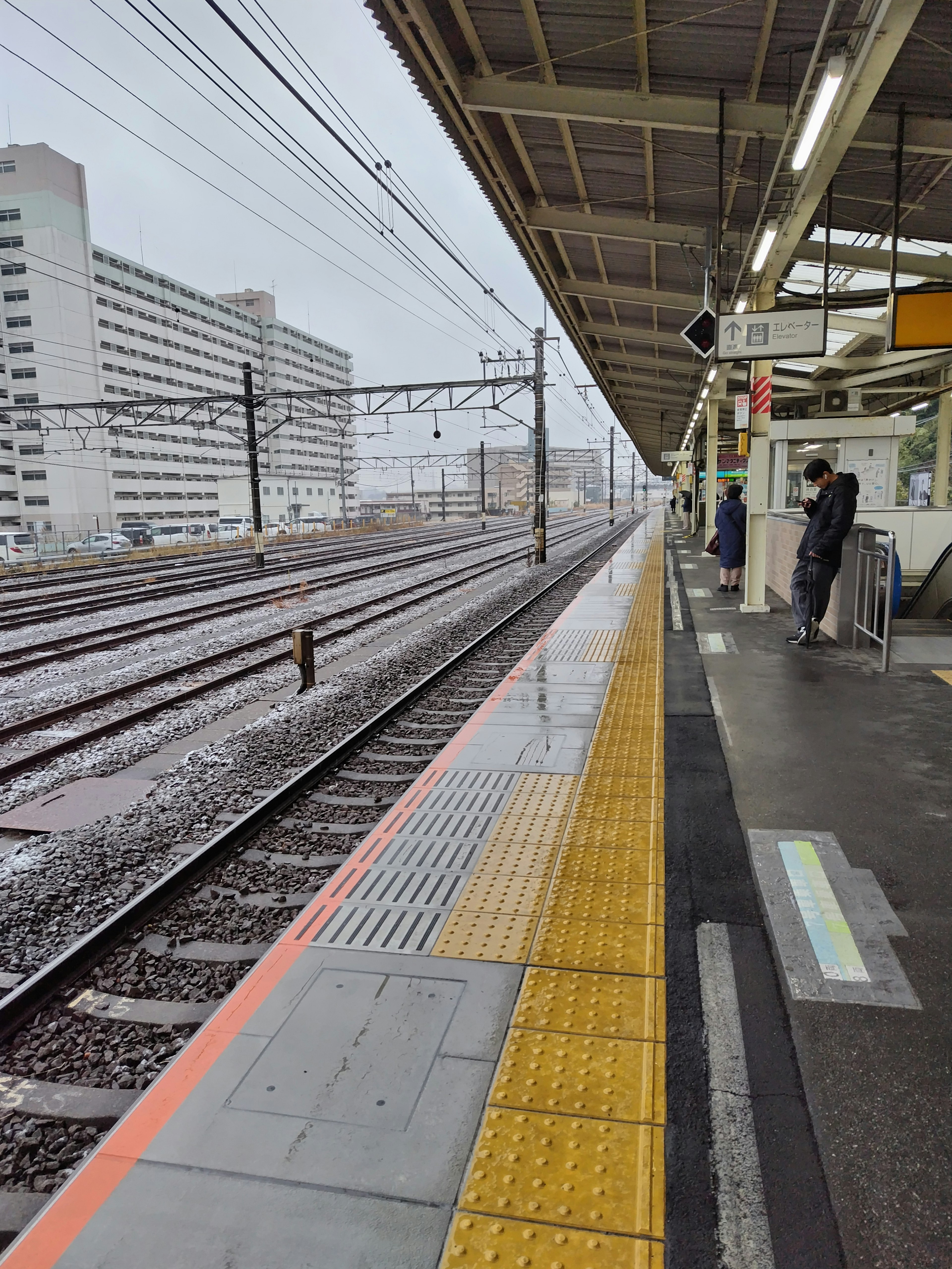 火车站平台的视图，有雨和轨道