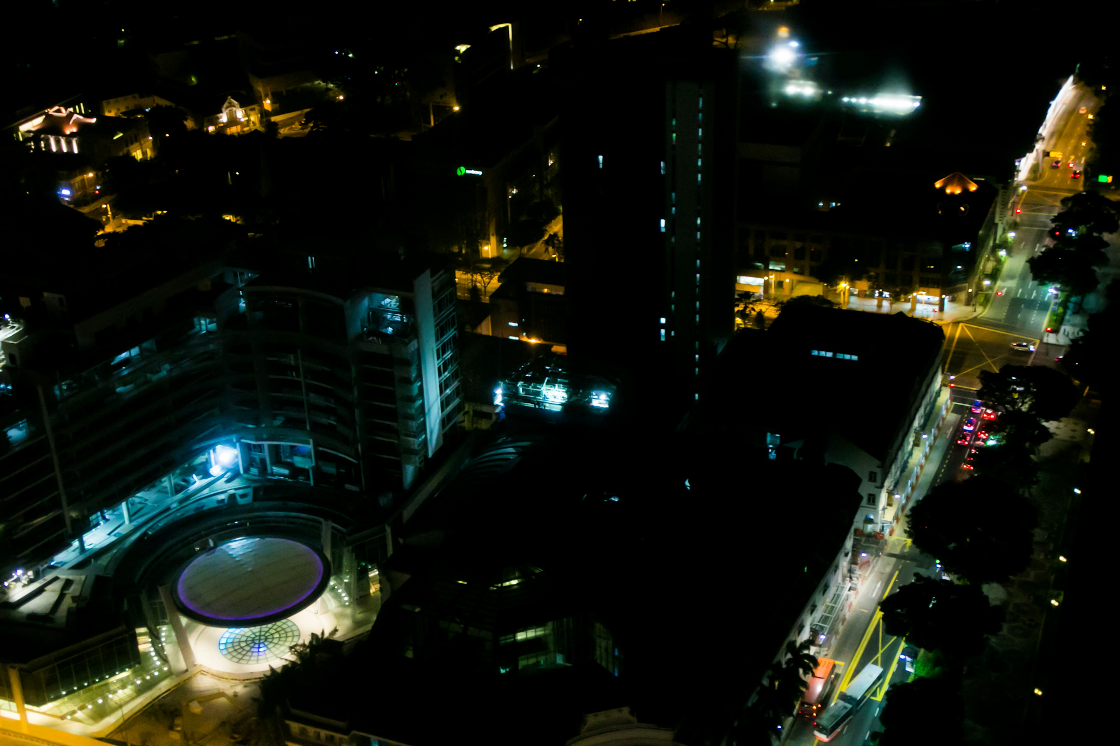 Vista aérea nocturna de una ciudad con edificios altos y calles iluminadas con luces azules