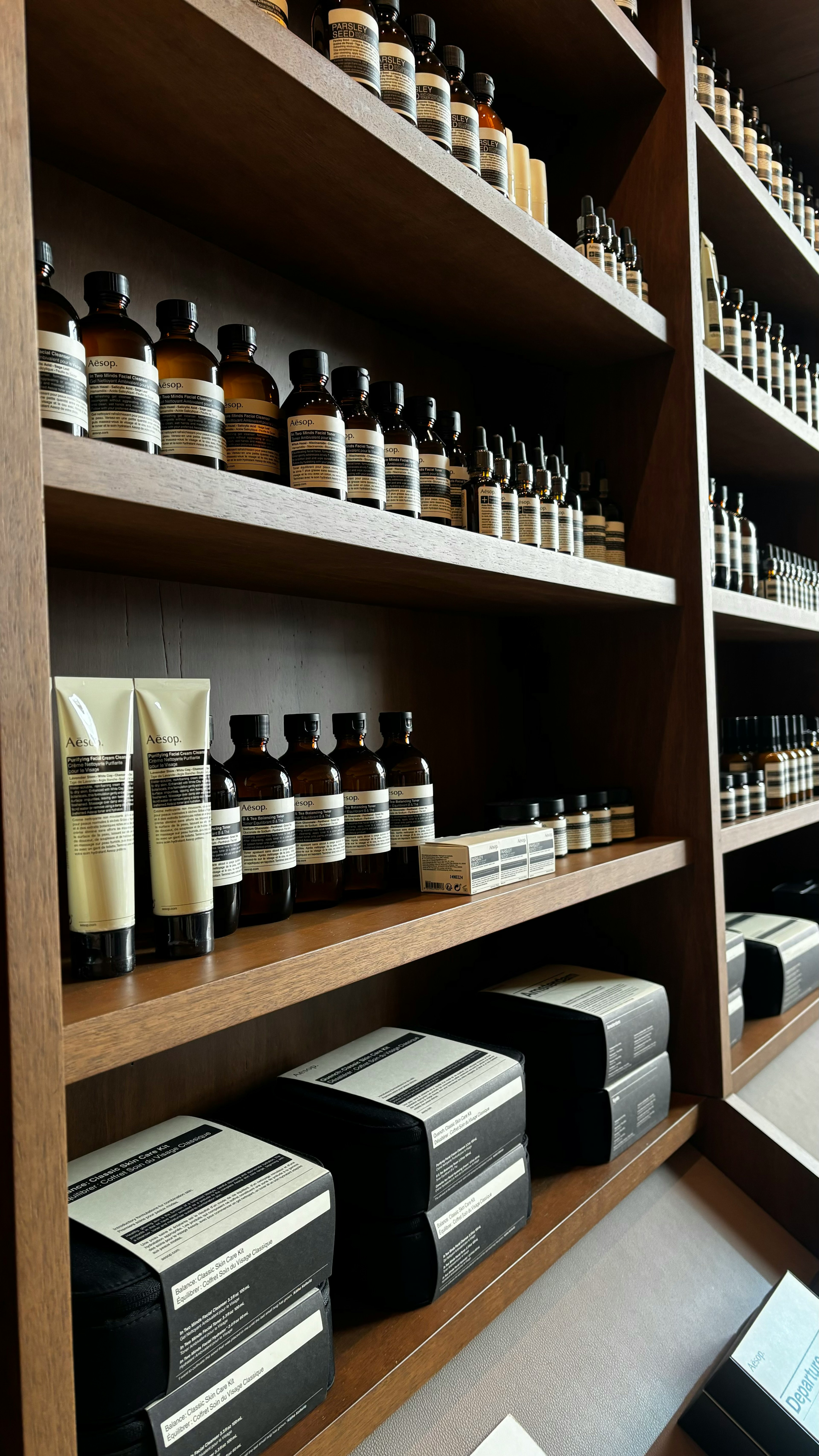 Neatly arranged bottles and packages of perfumes and body care products on wooden shelves