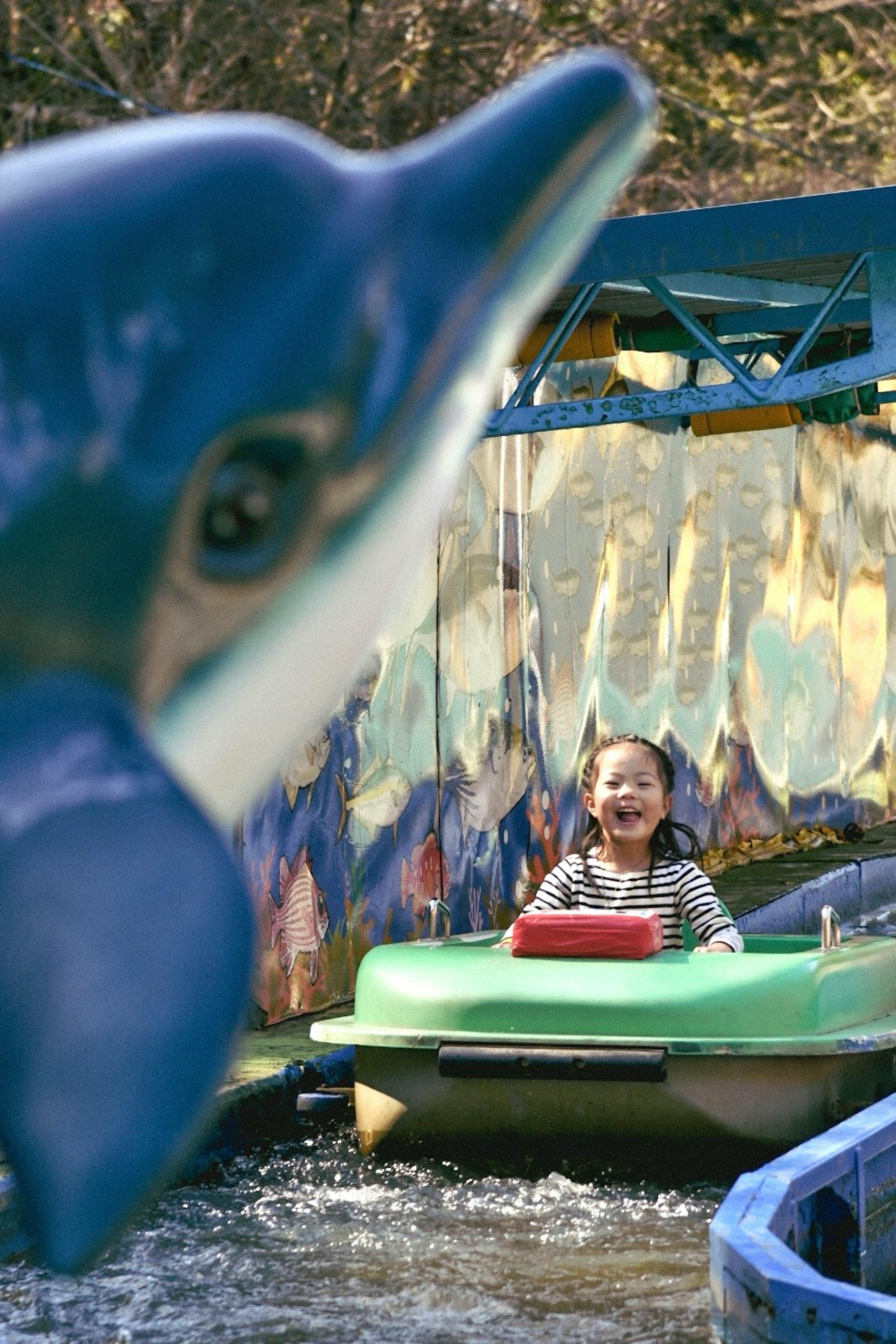 A child enjoying a boat ride with a dolphin statue in the foreground