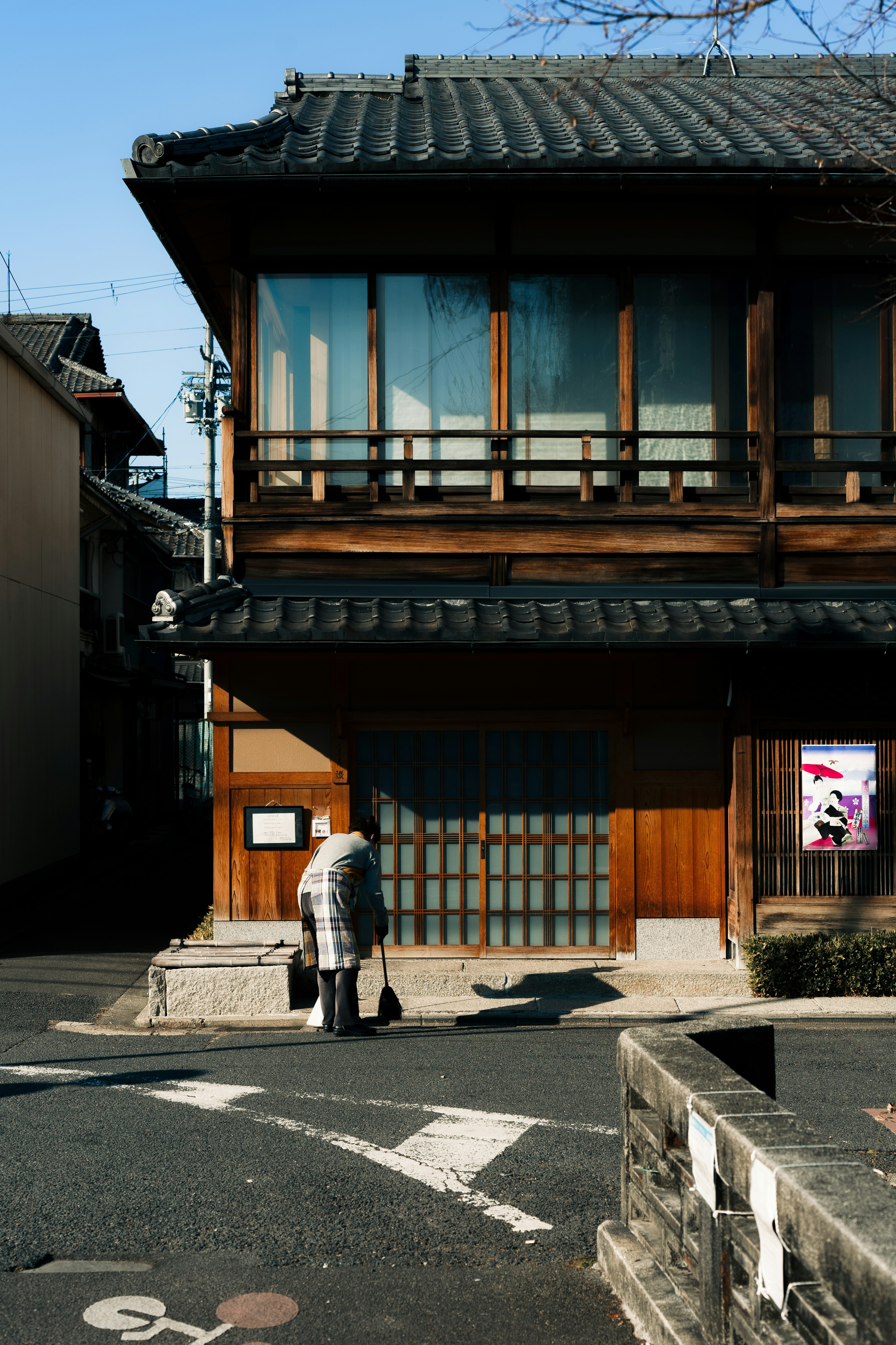 Personne âgée devant une maison japonaise en bois traditionnelle