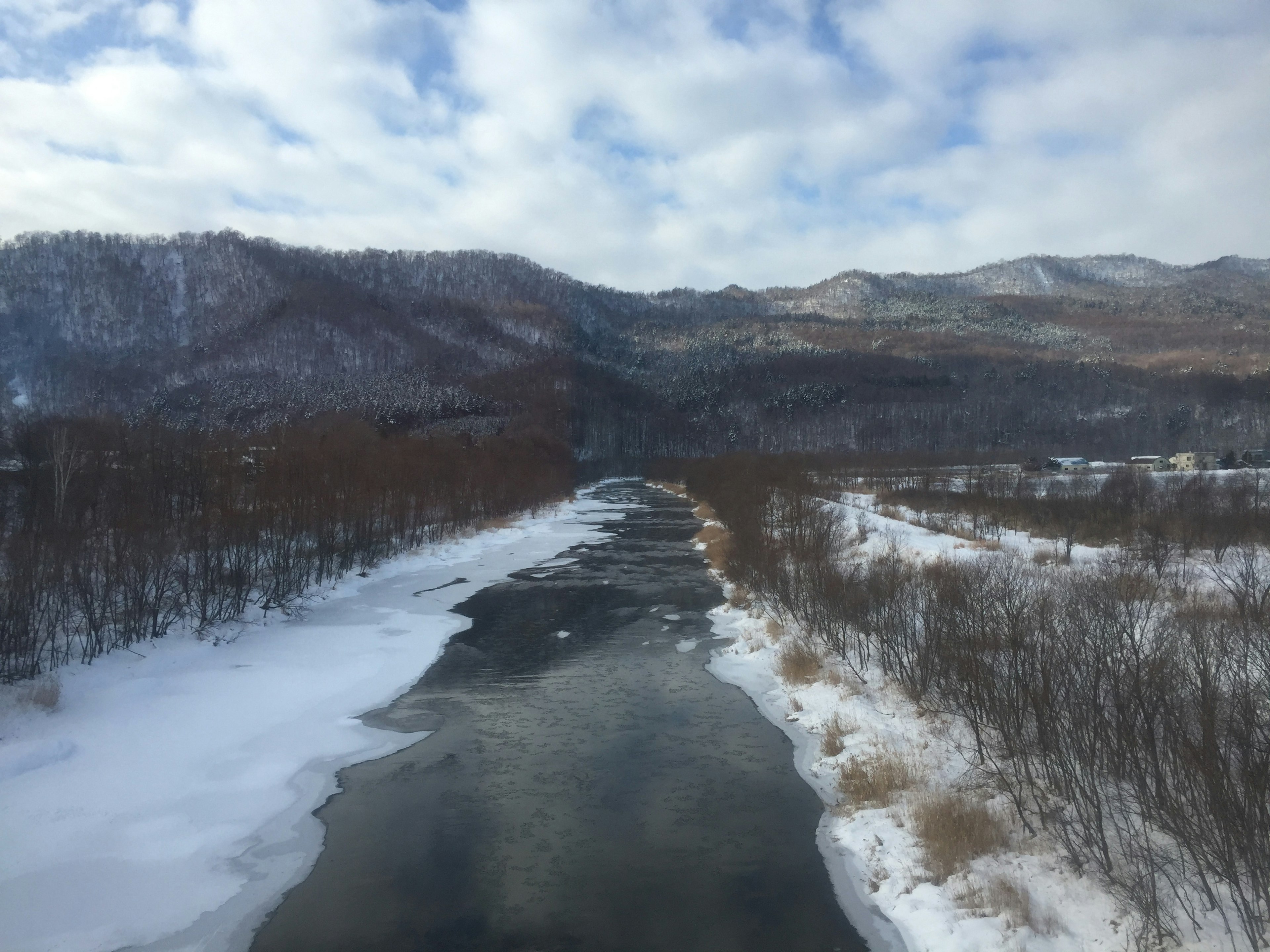 ทิวทัศน์ฤดูหนาวที่มีแม่น้ำที่ปกคลุมด้วยหิมะและภูเขา