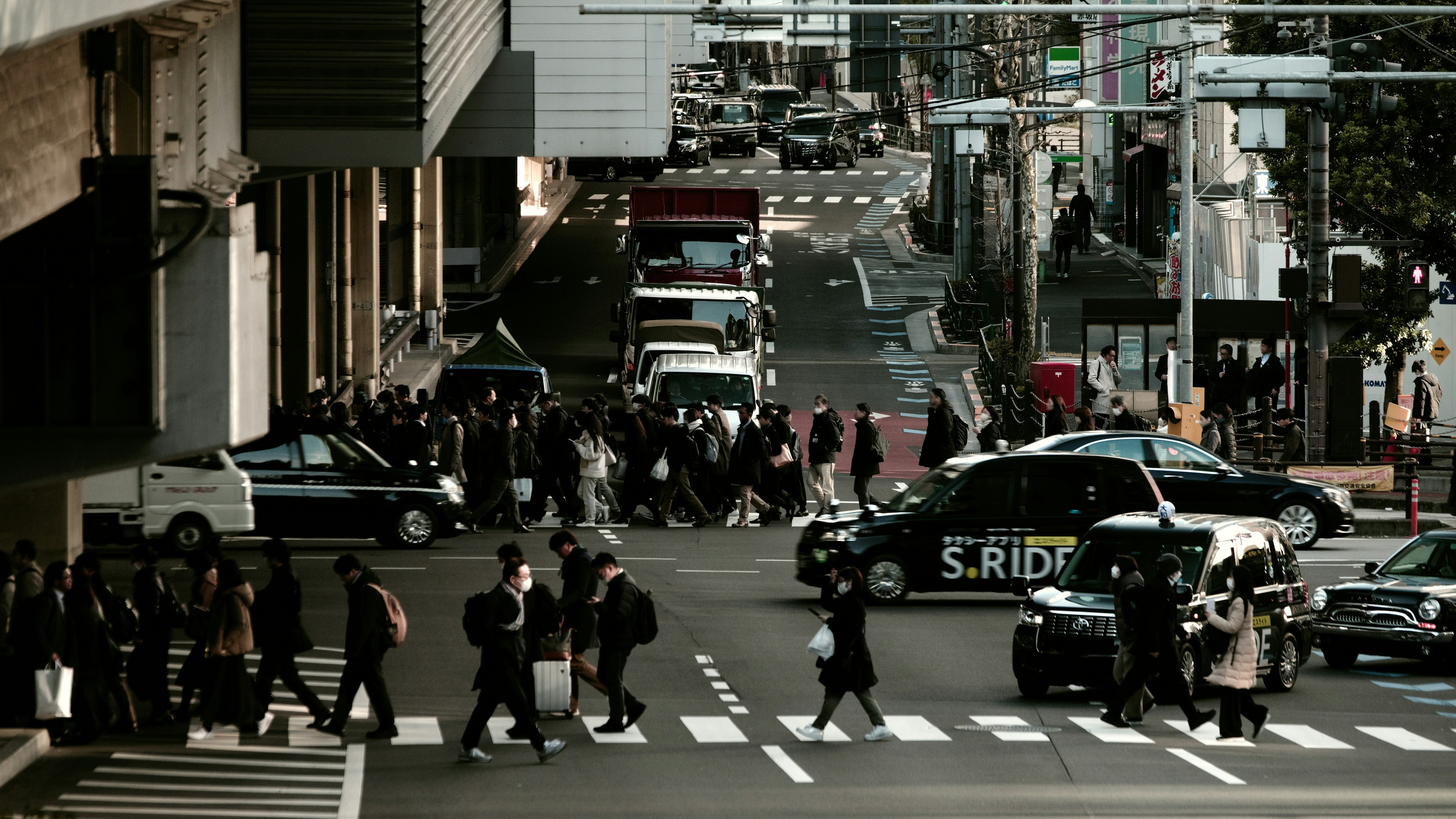 Urban scene with people crossing the intersection and vehicles in motion