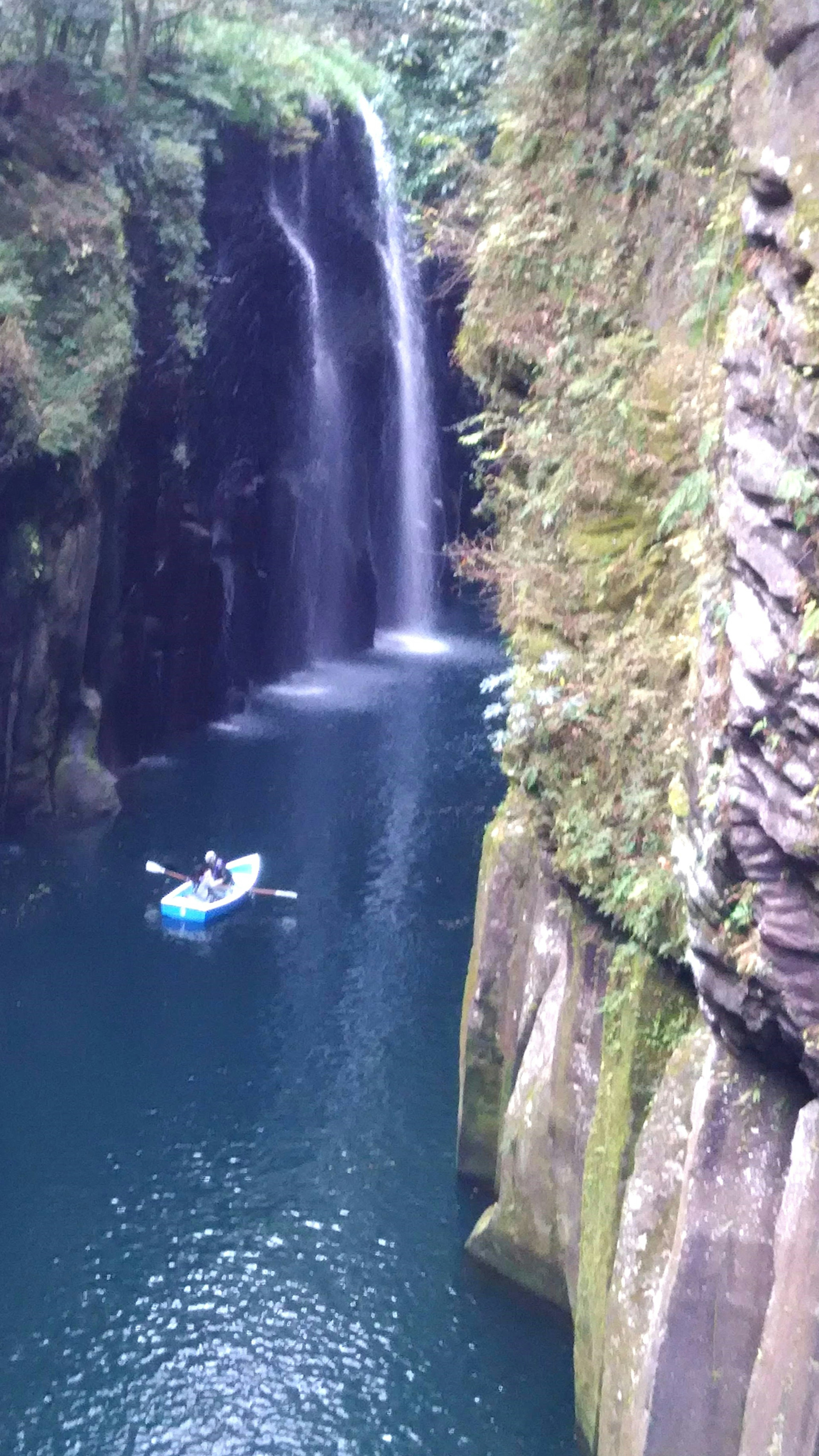 Un canyon pittoresco con un kayak blu che deriva vicino a una cascata